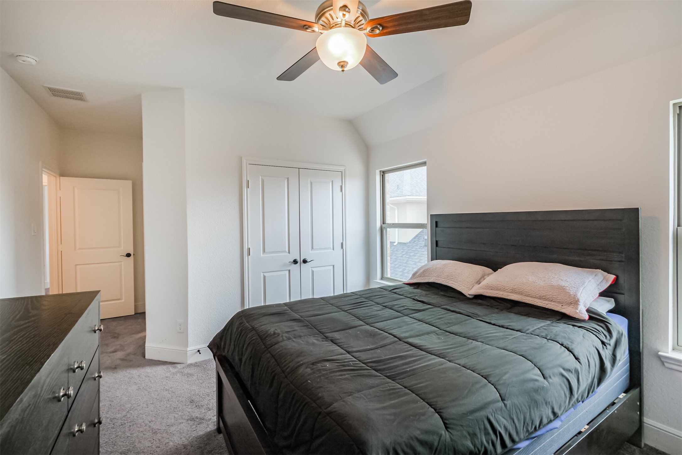 Inviting fourth bedroom located upstairs, featuring a dramatic vaulted ceiling, abundant natural light, and a spacious closet offering generous storage. A private en-suite bathroom completes the space, providing added comfort and convenience.
