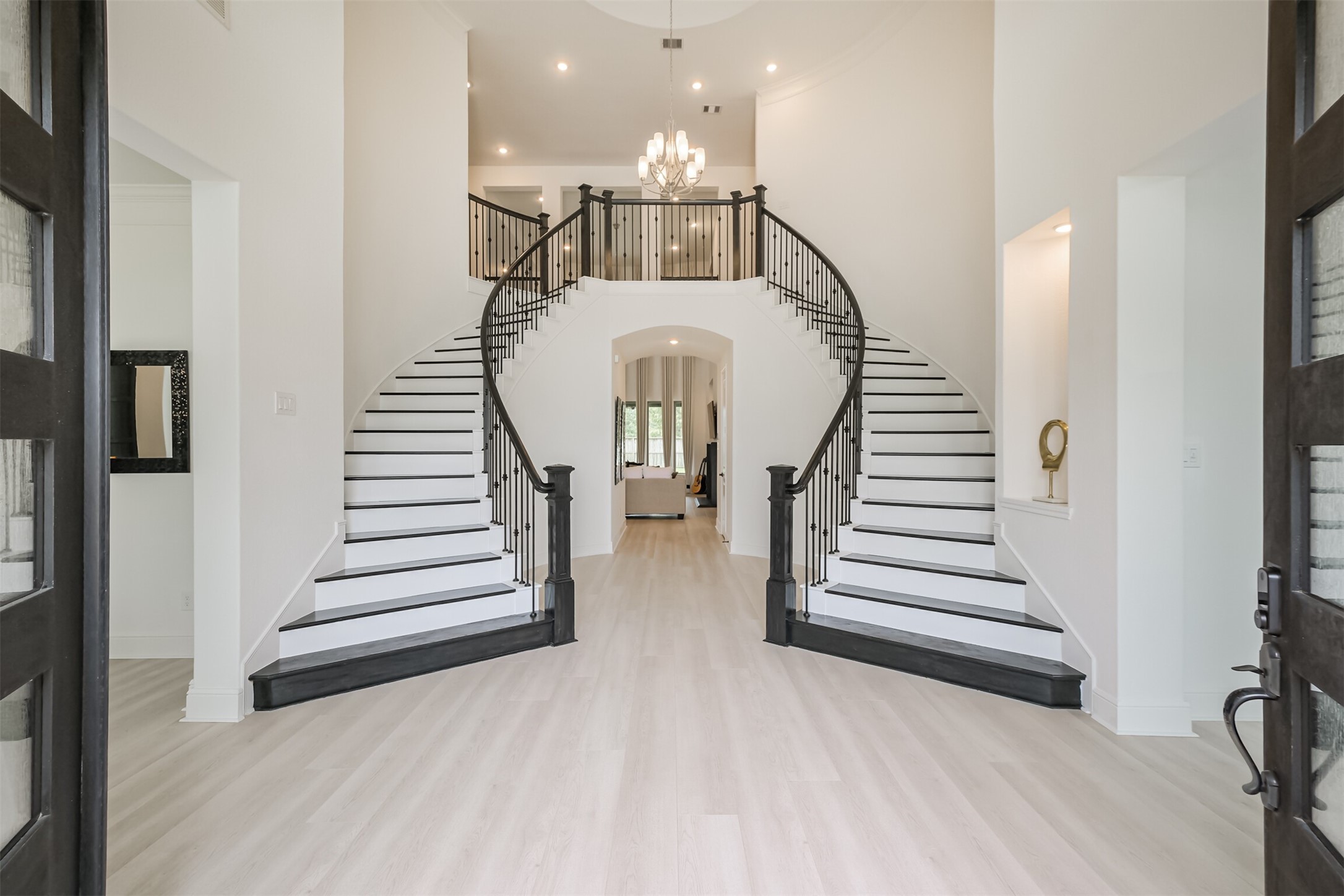 Impressive grand foyer featuring custom dual sweeping staircases, elegant chandelier lighting, and a bright, expansive layout that creates a breathtaking grand entrance the moment you step inside.