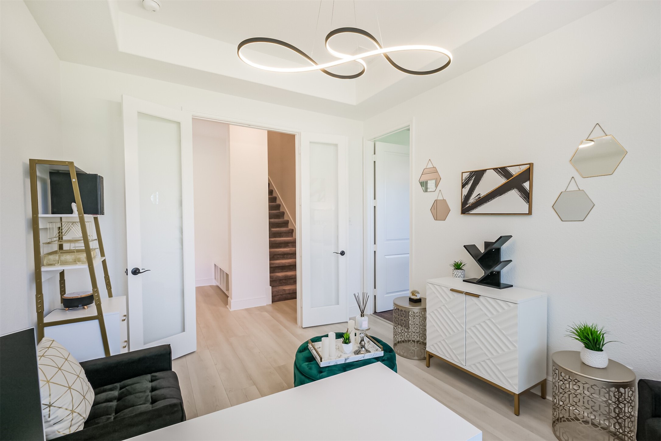 Another view of the private guest suite/third bedroom living area, ideally positioned off the homes second staircase and flowing seamlessly into the private bedroom. Double French glass doors, sleek white walls, and elegant contemporary lighting create a sophisticated, airy space with a polished modern aesthetic.