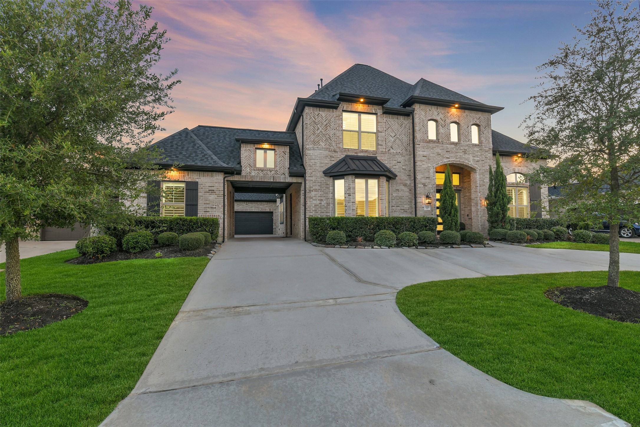 Commanding brick exterior showcasing timeless architecture and exceptional curb appeal, enhanced by sophisticated under-eave accent lighting that beautifully illuminates the home after sunset. A grand porte-cochre creates an impressive arrival, while a roof less than two years old adds lasting value to this distinguished residence.