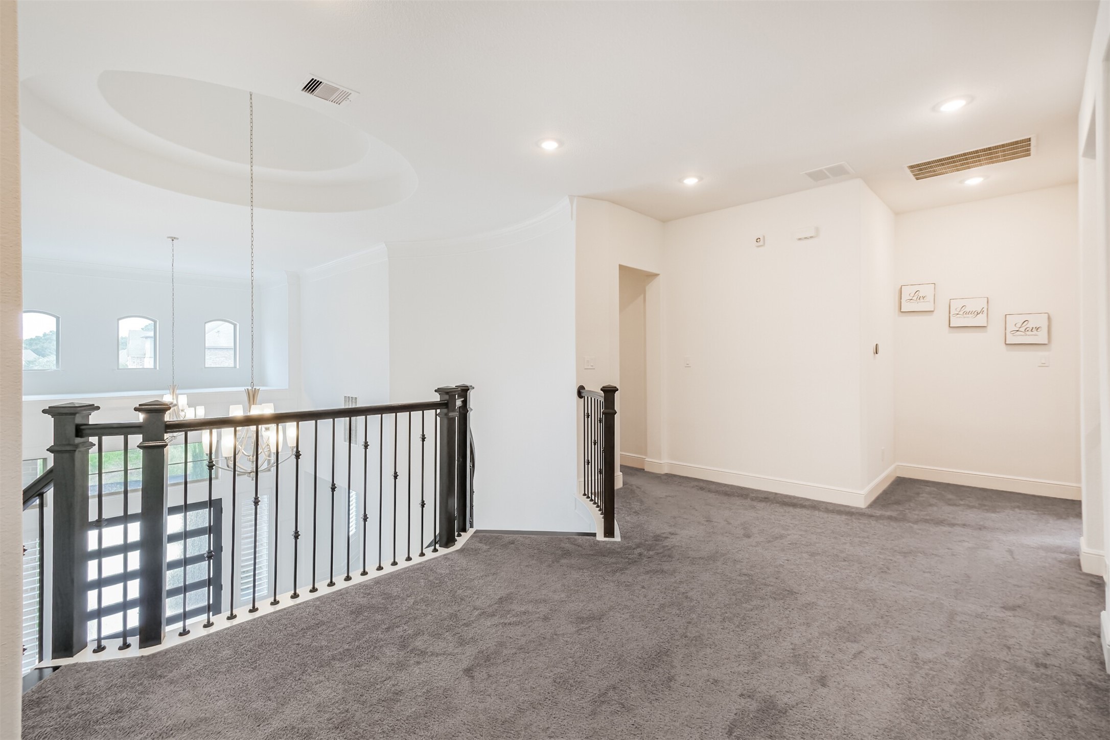 Elegant upstairs landing featuring plush carpeting and sophisticated wrought-iron railings overlooking the grand foyer below. Bright and spacious, this inviting area creates a graceful transition between the upstairs bedrooms while maintaining the homes open, impressive design.