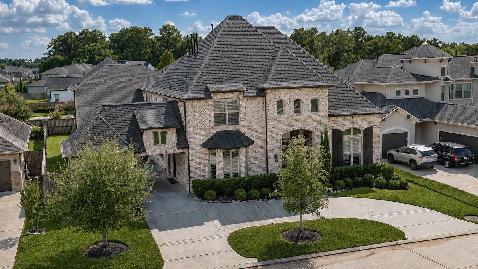 Commanding aerial view of this distinguished brick residence, showcasing timeless architecture, intricate brickwork, a grand porte-cochre, and an expansive curved driveway. Manicured landscaping and impressive rooflines complete the homes exceptional curb appeal and elegant arrival.