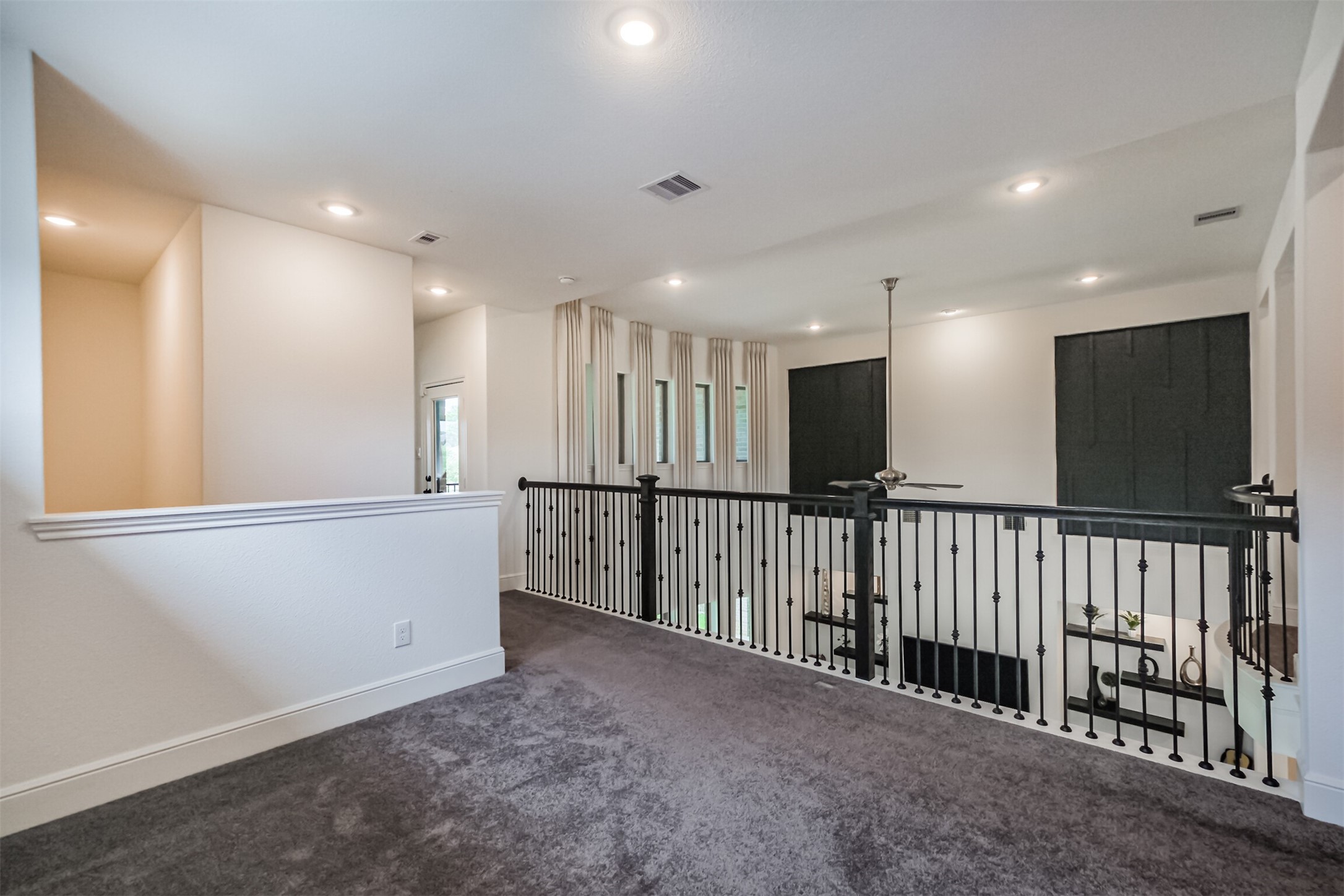 Expansive upstairs flex space featuring plush carpeting, elegant wrought-iron railings, and abundant natural light. Overlooking the main living area, this versatile space offers endless possibilities for a lounge, game room, media area, or additional gathering space.
