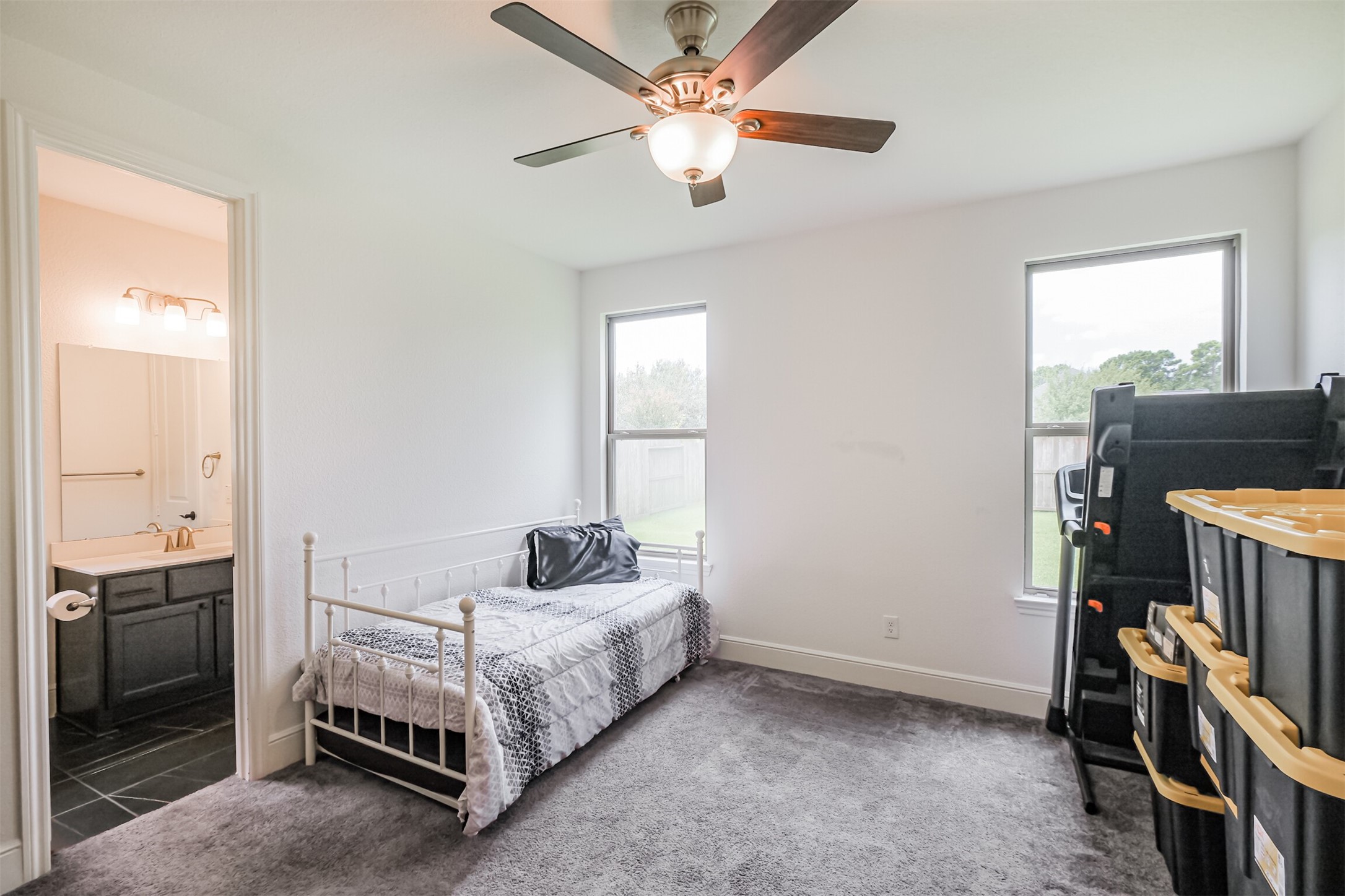 Bright and inviting downstairs guest suite/third bedroom featuring expansive windows that fill the space with natural light, a ceiling fan for added comfort, and a private en-suite bathroom, creating a comfortable and secluded retreat for guests.