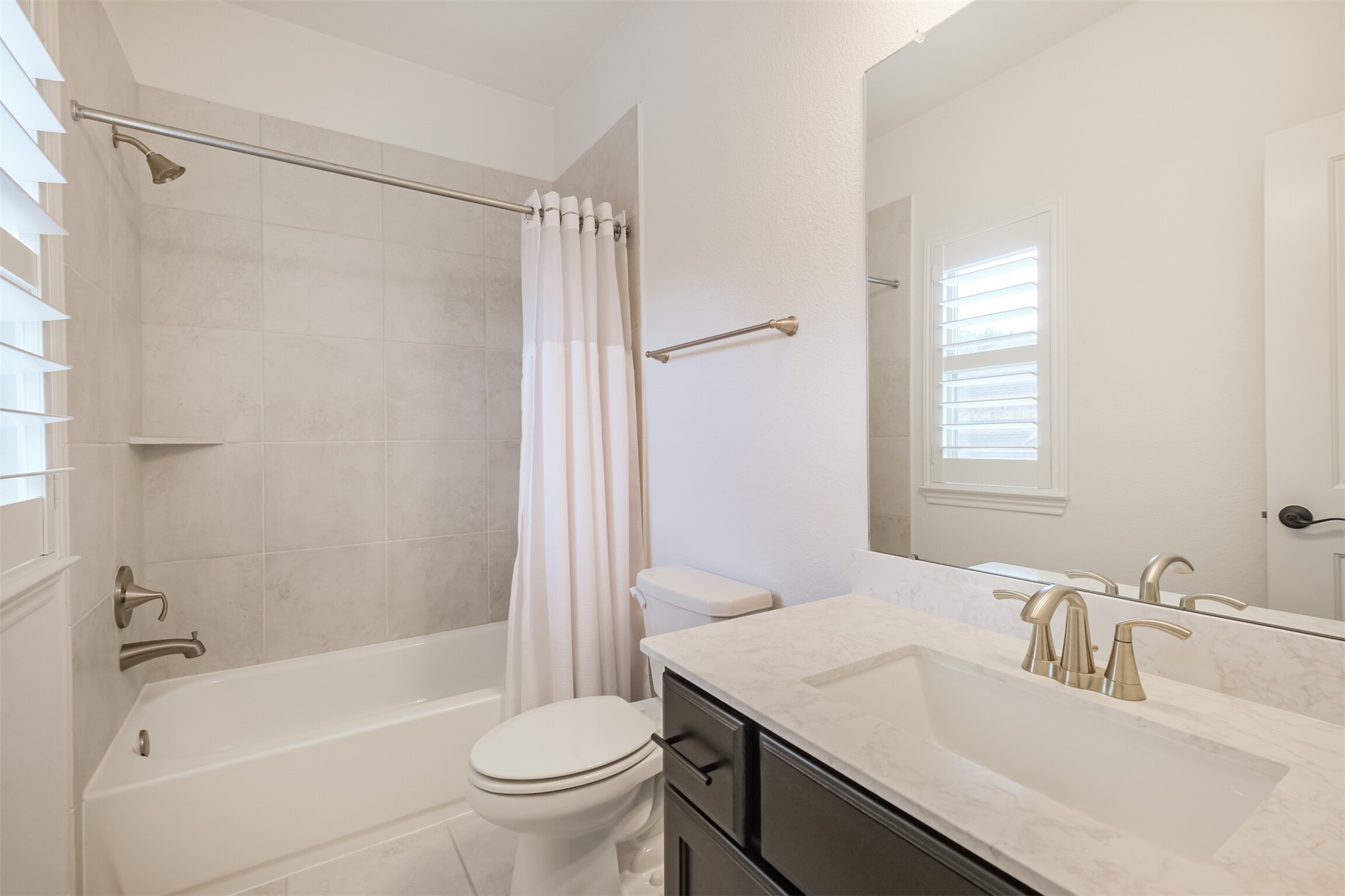 Bright and contemporary seventh en-suite bathroom featuring a sleek vanity, elegant fixtures, and a beautifully tiled tub and shower combination. Clean lines and modern finishes create a polished, tranquil retreat.