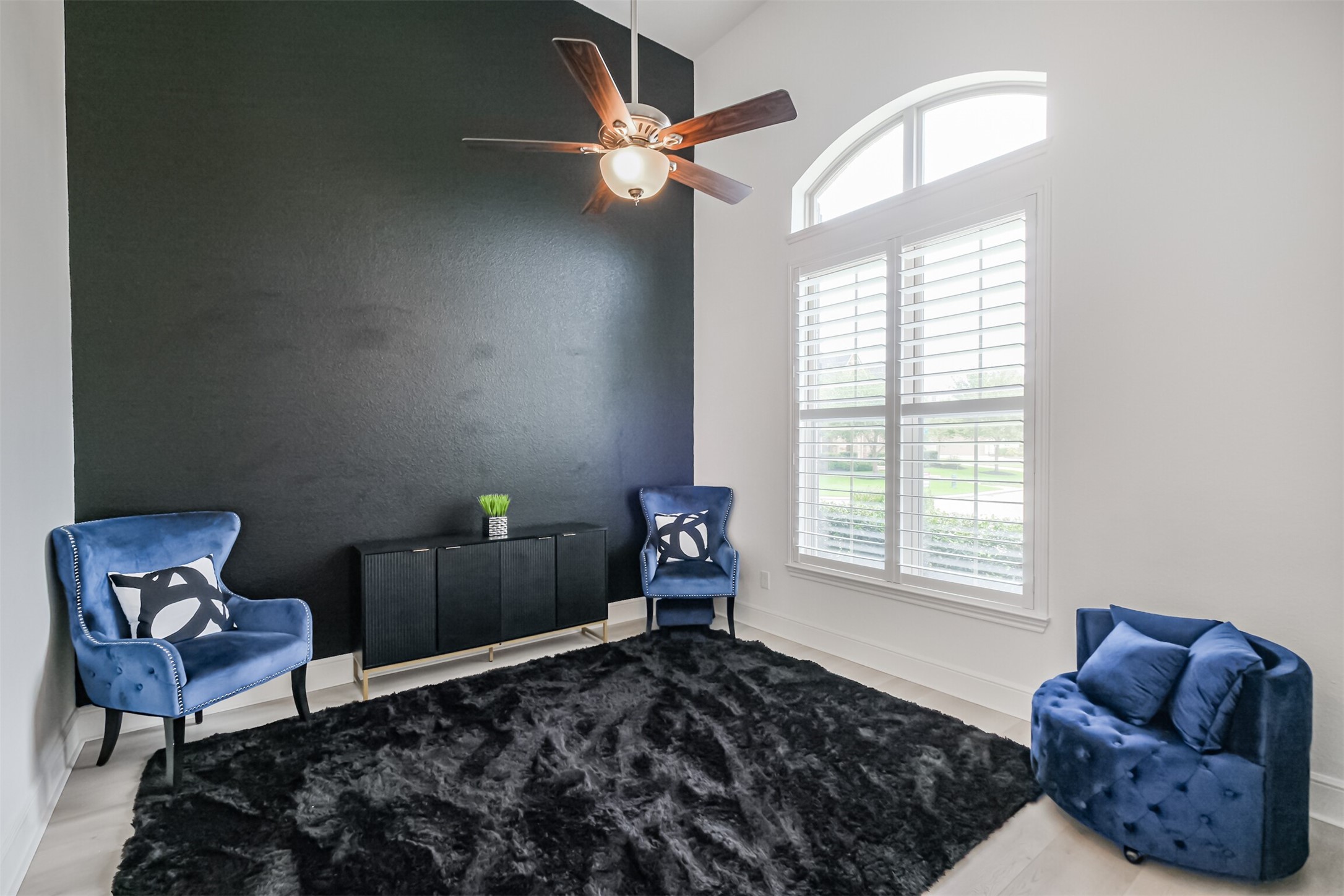 The sophisticated study, ideally positioned just off the grand foyer, features soaring ceilings and abundant natural light streaming through an impressive arched window framed by classic plantation shutters.