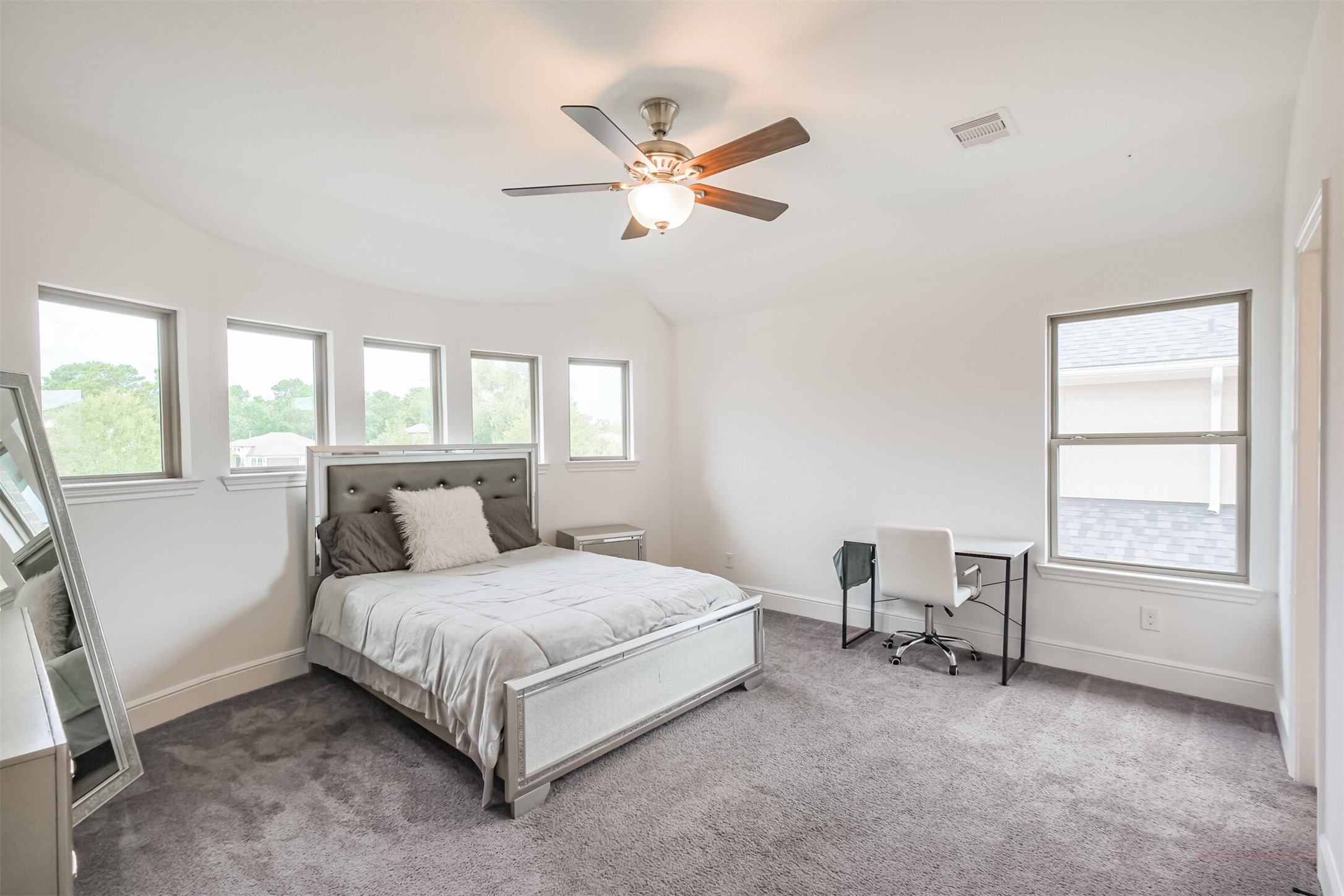 Spacious second primary suite featuring multiple windows that fill the room with natural light, plush carpeting, and a ceiling fan for added comfort. A private en-suite bathroom completes this generously sized retreat, offering both privacy and convenience.