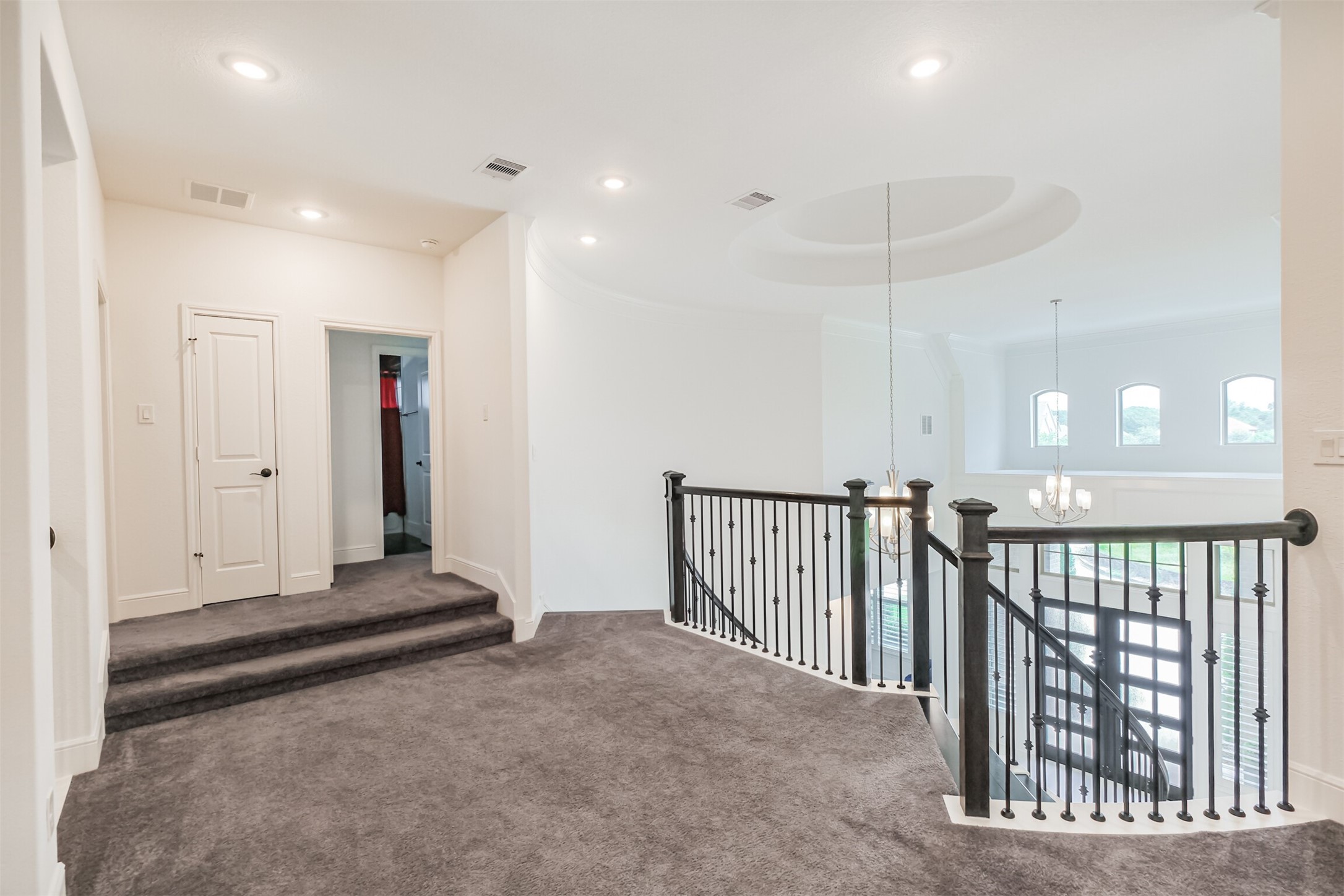 Expansive upper-level landing featuring elegant wrought-iron railings, plush carpeting, and oversized windows that fill the space with abundant natural light, creating a graceful transition between the homes upstairs living areas.