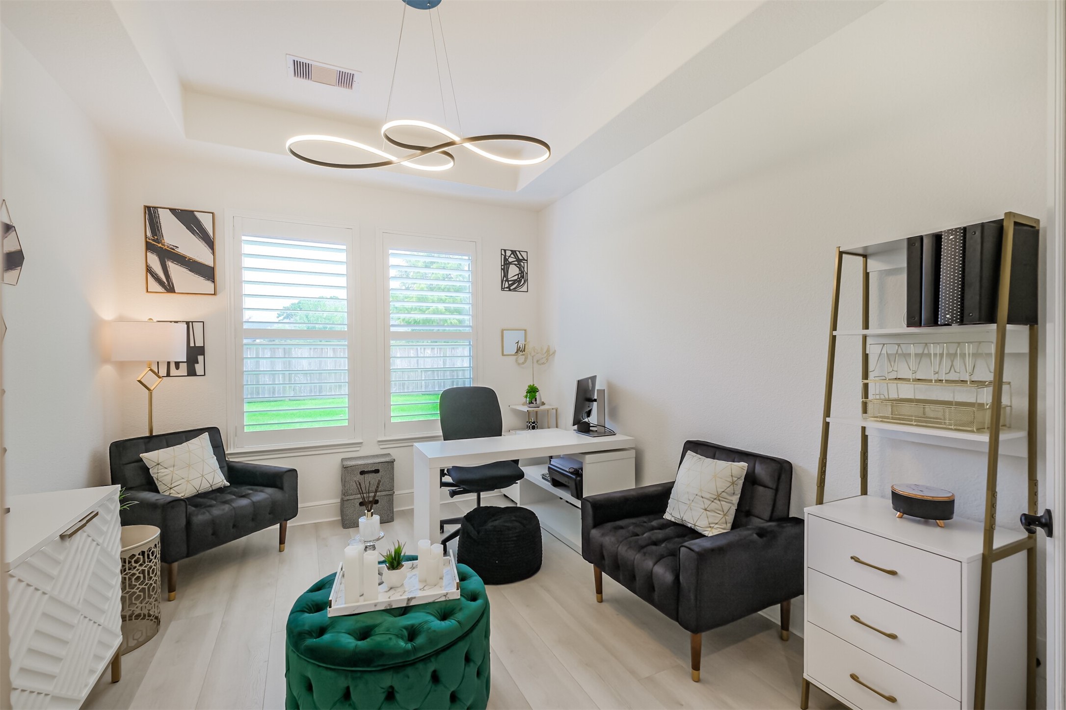 Bright and versatile living area within the private guest suite/third bedroom, offering the flexibility to serve as a comfortable sitting room or sophisticated home office. Modern lighting and expansive windows fill the space with natural light while providing peaceful views of the outdoors.
