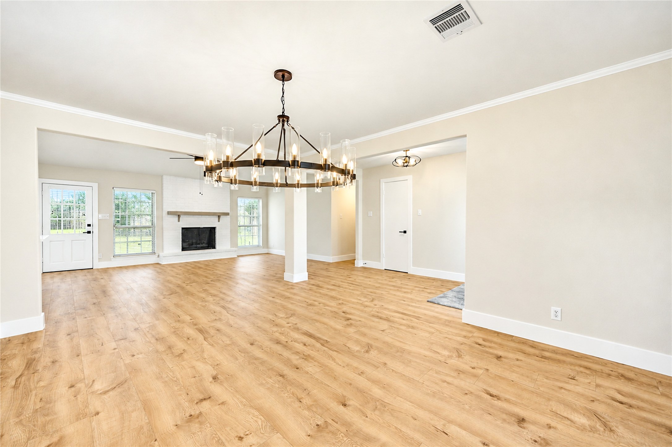 Expansive view highlights the open flow between the dining and family rooms, featuring new engineered wood flooring, contemporary ceiling fans, and updated lighting throughout.