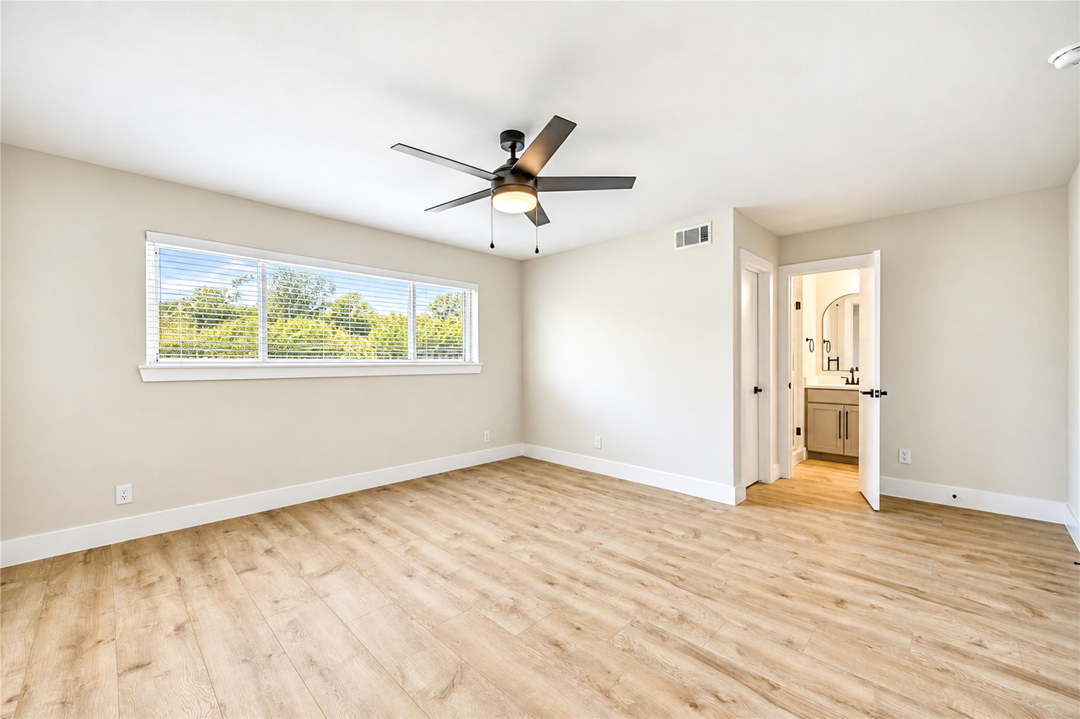 Another view of the primary suite, featuring two walk-in closets, including an oversized closet with a wall mirror and built-in shelving for exceptional storage.