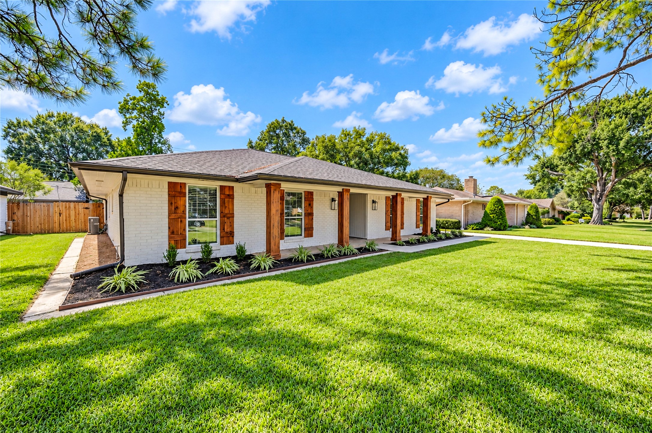 Inviting entrance showcases a new front door with frosted-glass sidelights, cedar-look columns, and updated exterior lighting.