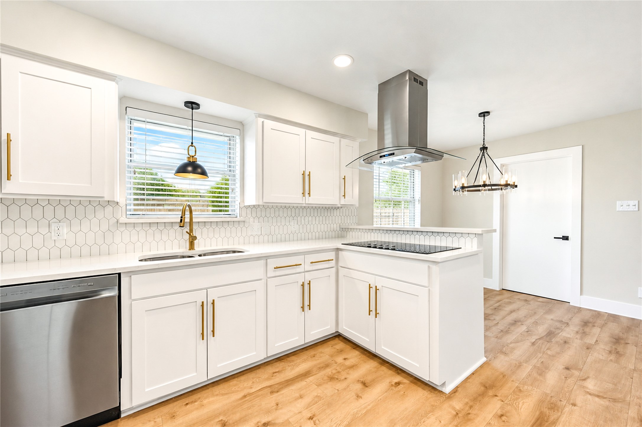 Bright kitchen features quartz countertops, designer backsplash, stainless steel appliances, and a convenient breakfast bar overlooking the adjoining living spaces.