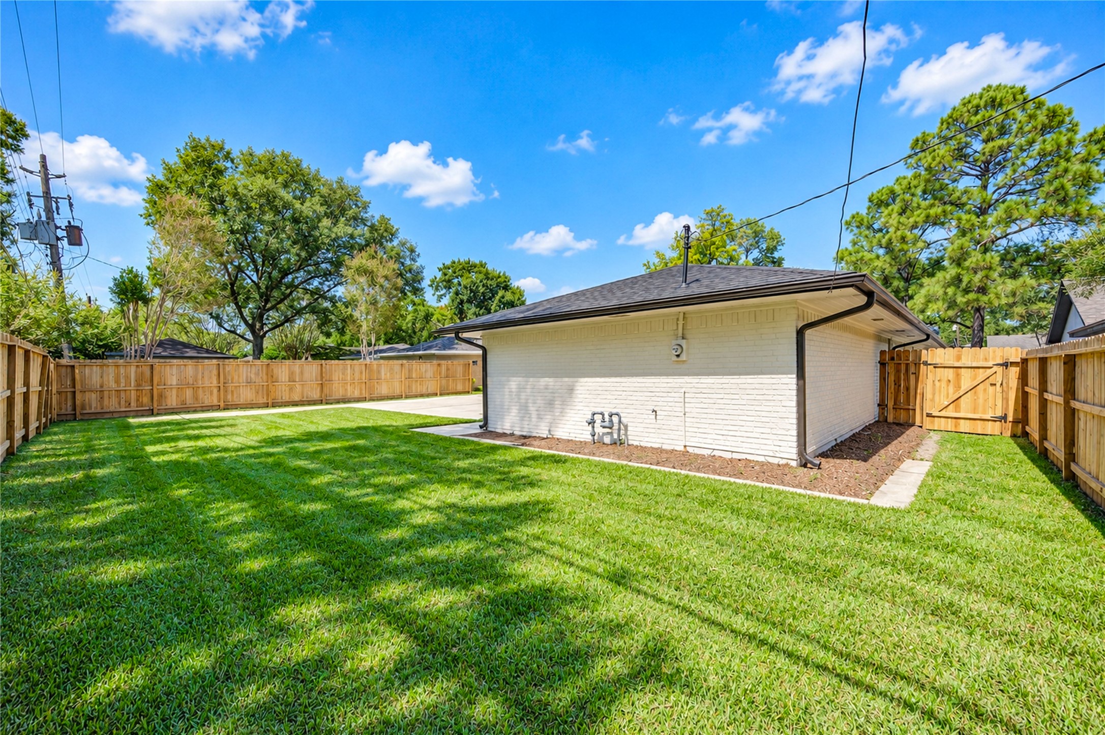 Beautiful backyard offers lush green lawn, privacy fencing, and ample space for a future swimming pool, playground equipment, or outdoor entertaining area.