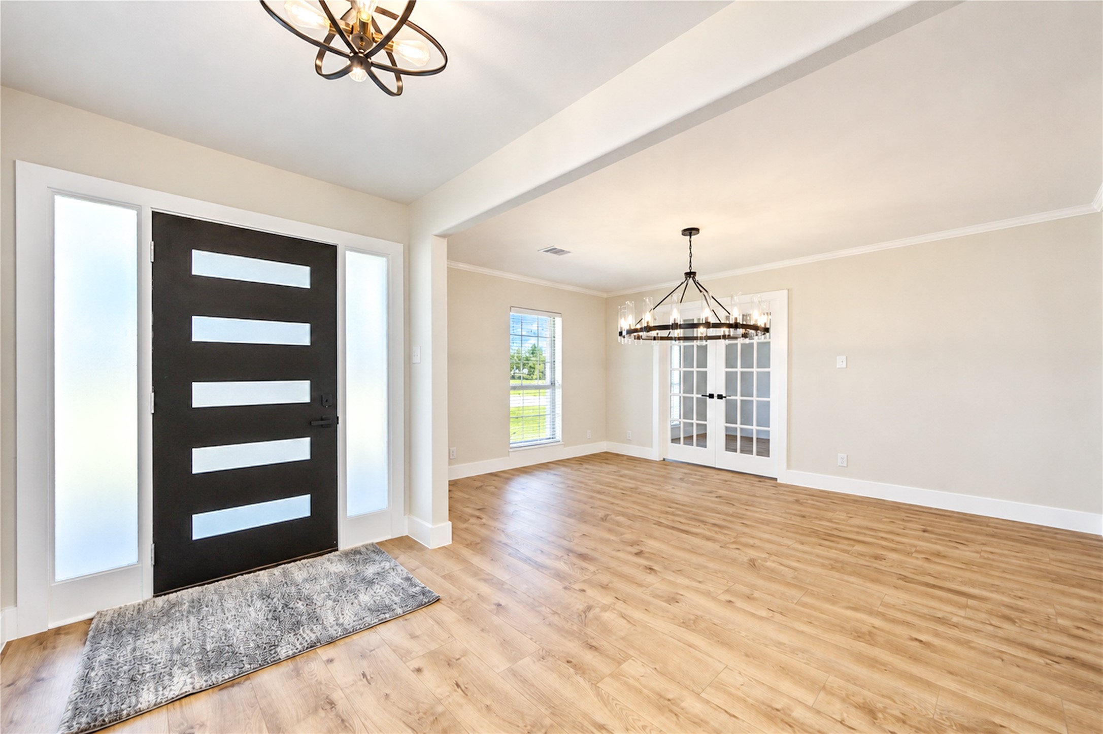 Beautifully updated entry features a contemporary front door with frosted-glass sidelights for privacy, new wide-plank engineered wood flooring, and crisp Shaker-style door casings and baseboards carried throughout the home.