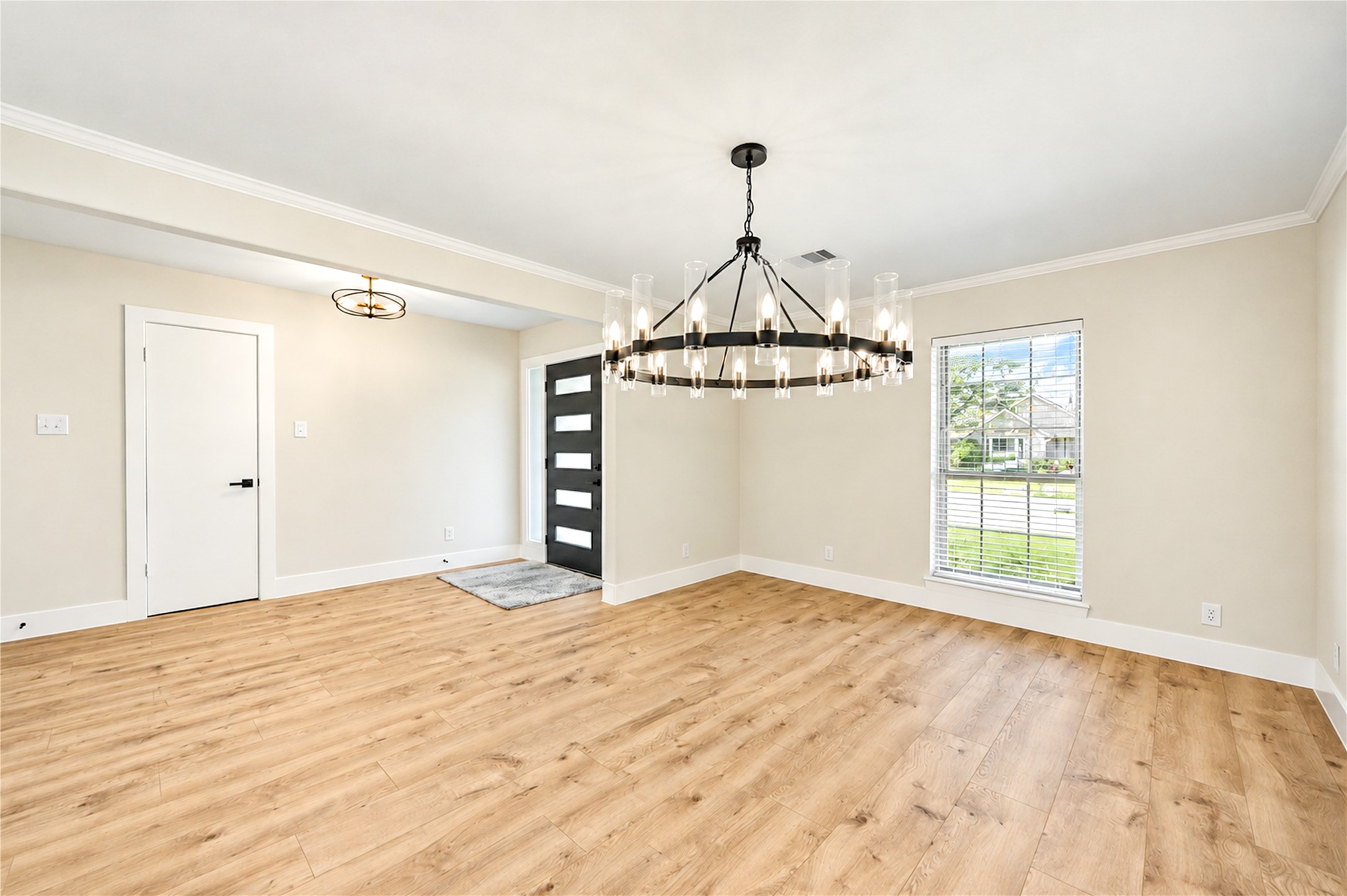 Elegant formal dining room features crown molding, abundant natural light, new wide-plank engineered wood flooring, and a stunning new statement chandelier.
