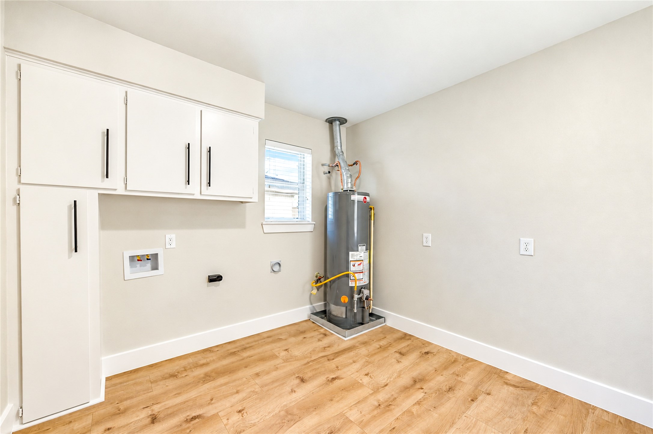 Spacious 10x10 laundry room features abundant cabinetry and storage along BOTH walls, new wide-plank engineered wood flooring, and a convenient exterior door providing direct access to the covered patio!