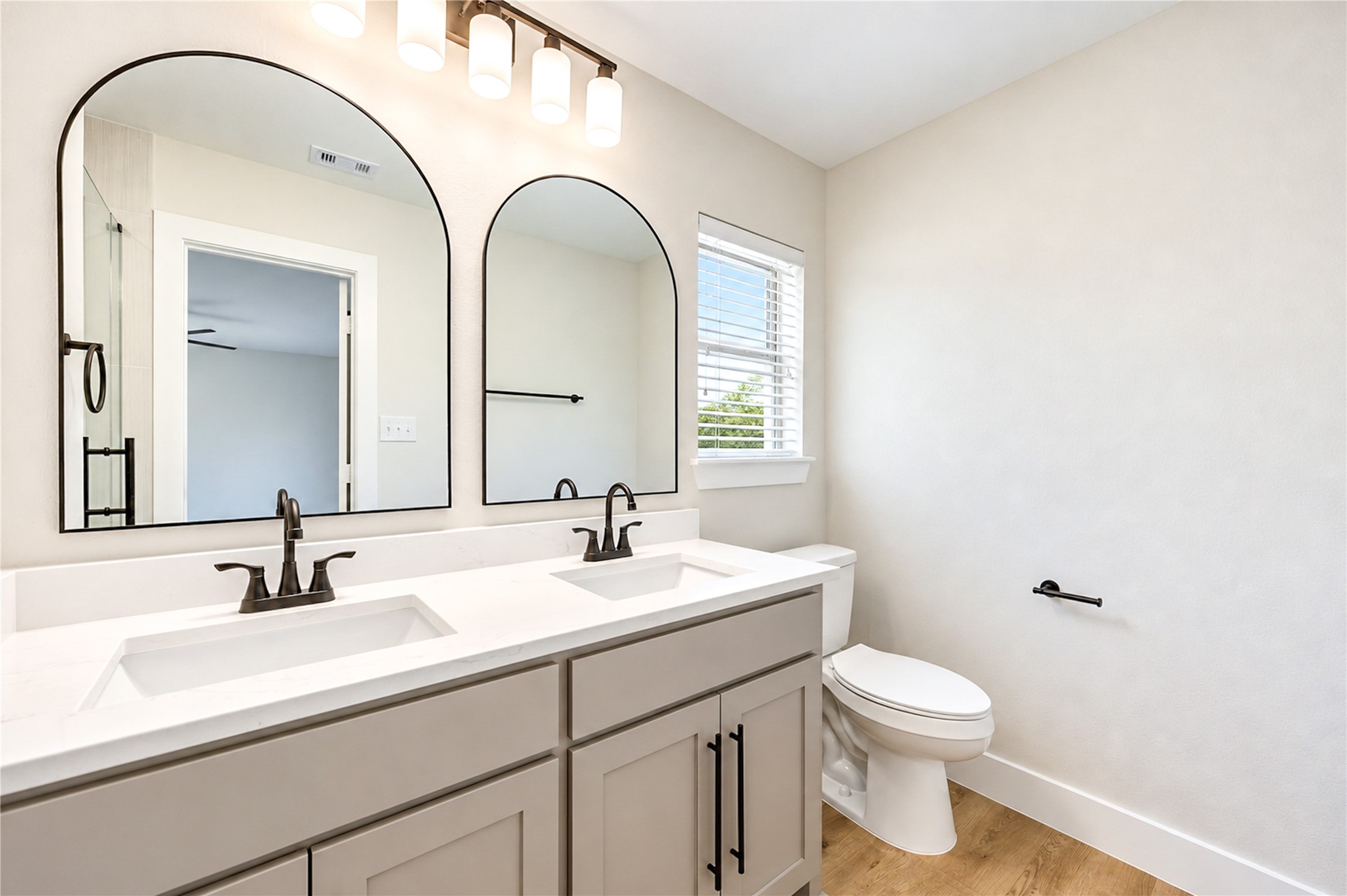 Completely updated primary bath features new sinks, faucets, toilet, plumbing fixtures, and supply lines, complemented by a spacious dual-sink vanity.