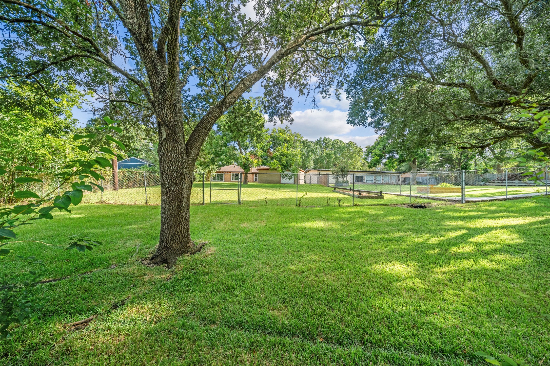 A great view of the home and property from boat dock.  Yard is fully fenced and ready for your pets!  In the right of the photo within the fence is a garden.