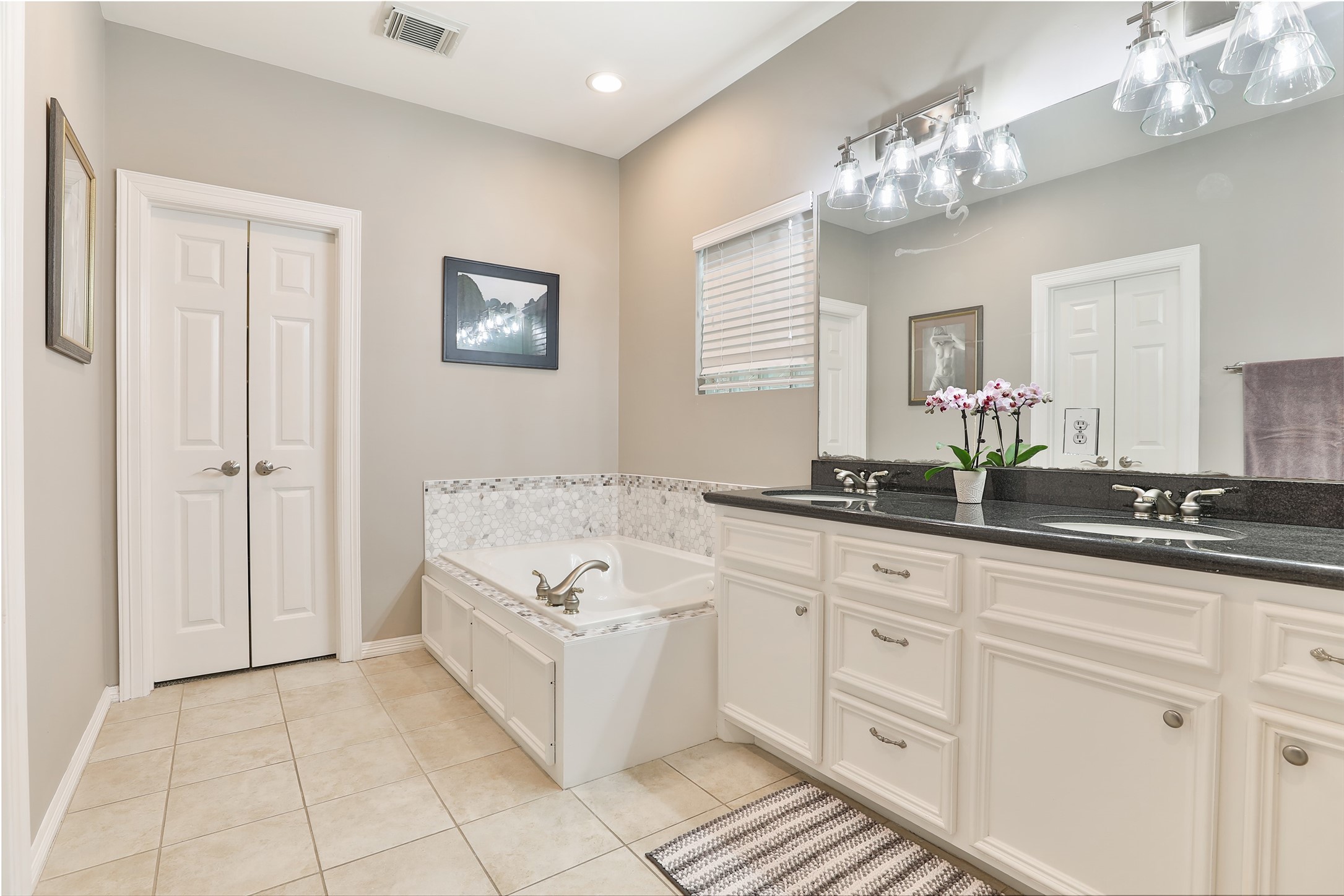 Primary bathroom with dual sinks, a jetted tub, beautiful walk-in shower and two walk-in closets.