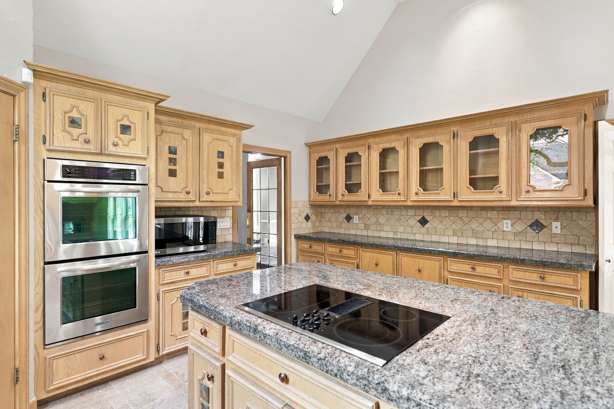 The impressive 8-foot center island features a GE 4-burner electric cooktop and abundant counter space for meal preparation and entertaining. Additional appliances include convenient KitchenAid double convection ovens and an LG countertop microwave, making this Kitchen as functional as it is spacious.