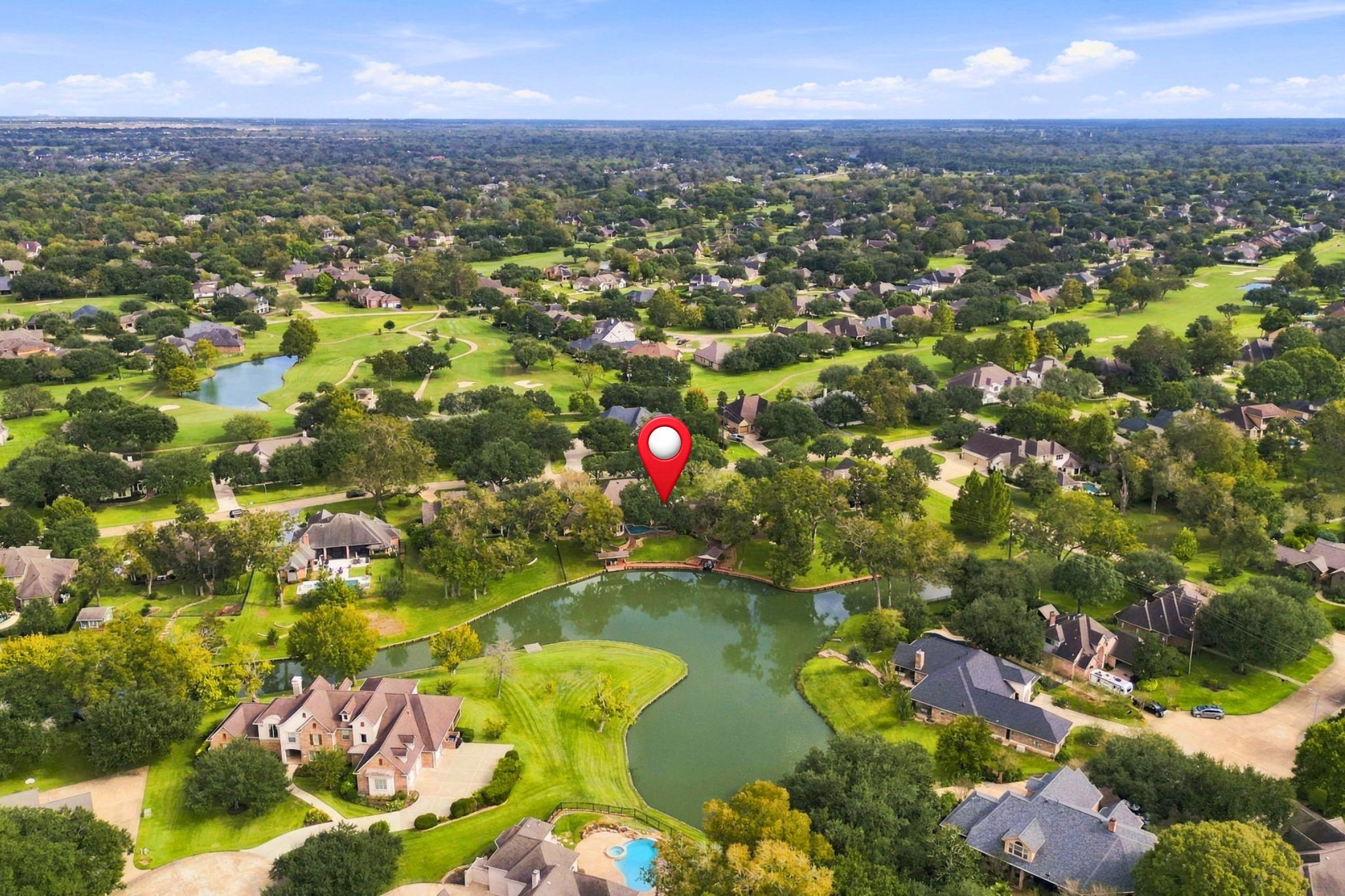 This view looks east toward the rear of the property, with the estate pinpointed for easy identification. The aerial perspective highlights its beautiful setting along Pecan Lake, with scenic views of the golf course in the distance.