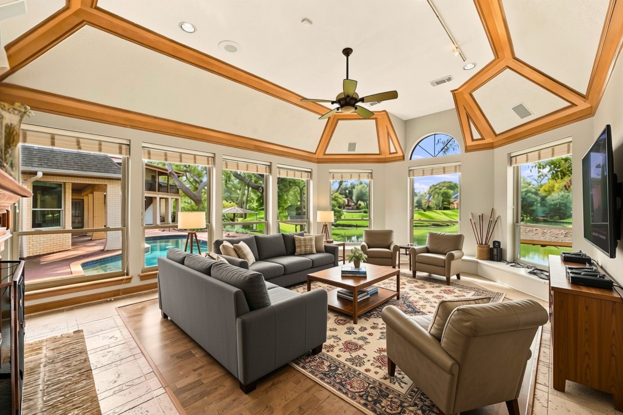 On the opposite side of the double-sided fireplace is a wonderful, versatile flex space that can serve as a Game Room, Media Room, or additional gathering area. Featuring impressive 12-foot ceilings, elegant wood ceiling crown molding, and two walls of windows, this inviting room captures incredible panoramic views of the resort-style backyard, pool and spa, and beautiful Pecan Lake beyond. A perfect space to relax, entertain, and take in the exceptional waterfront setting!