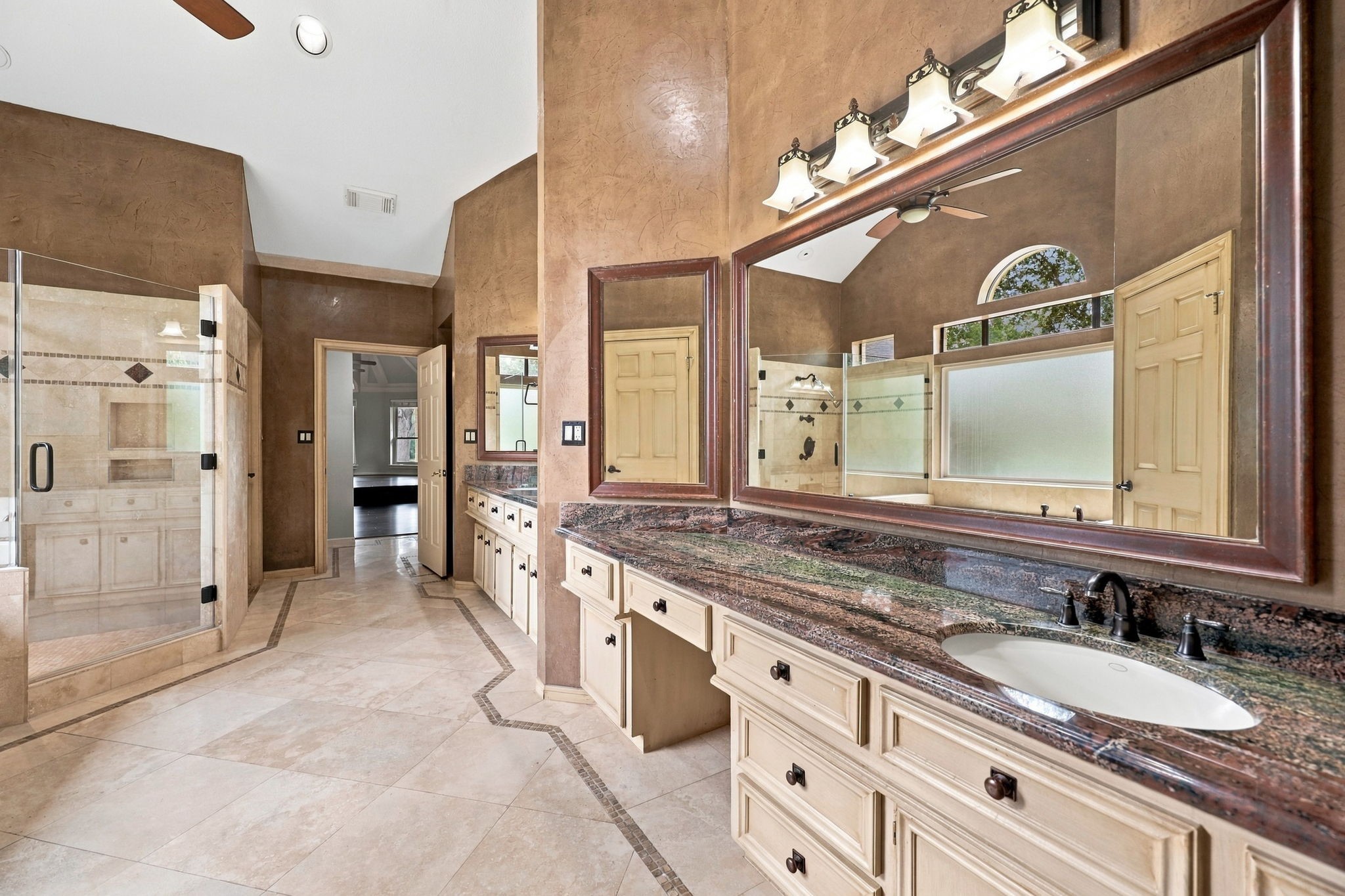 The second vanity area features a spacious granite countertop with an undermount sink, an oversized framed mirror, and elegant oil-rubbed bronze widespread faucets. Coordinating light fixtures complete the look, adding a warm and sophisticated touch to this beautifully appointed Primary Bath.