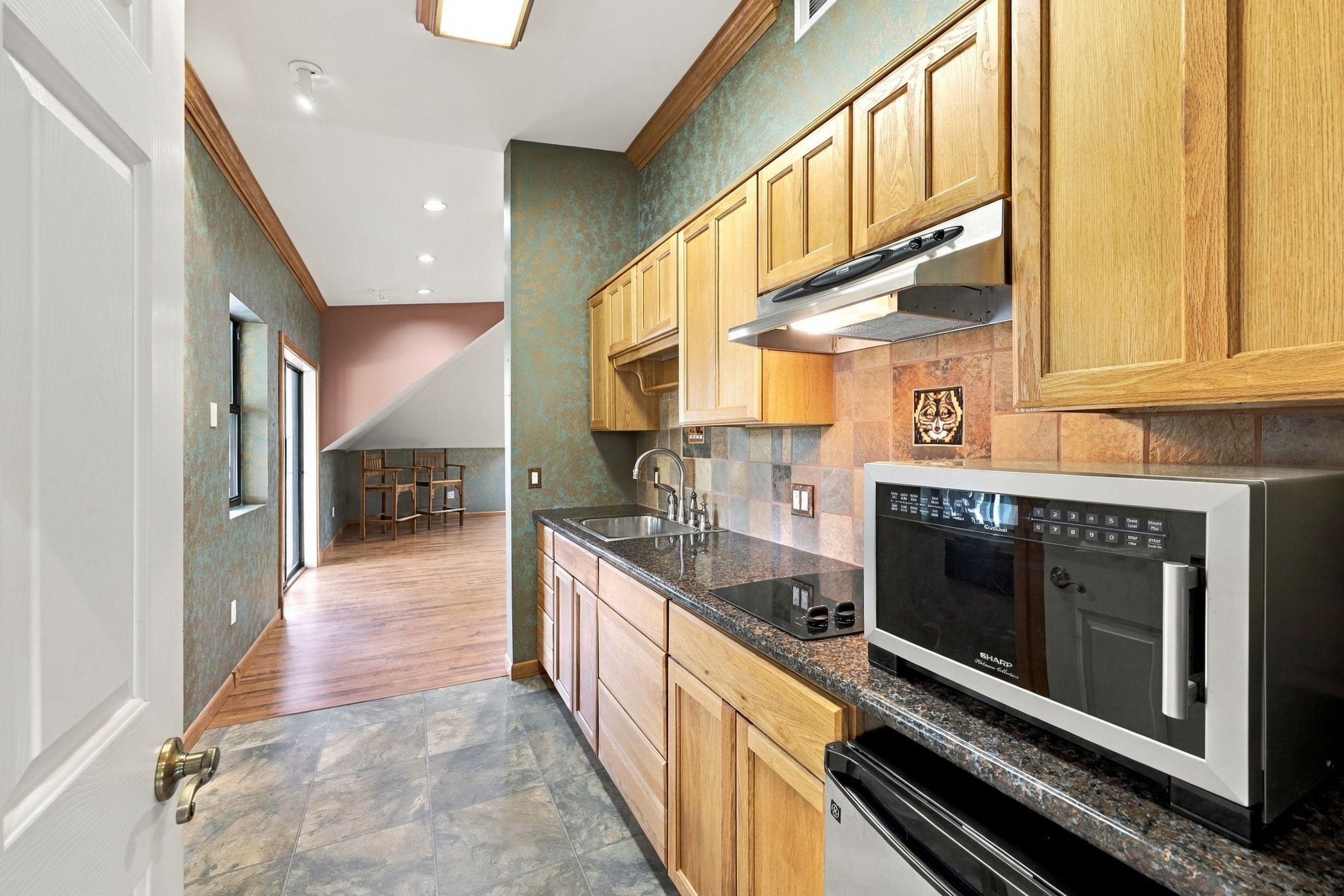 The apartment Kitchen is equipped with granite countertops, a stainless-steel sink, a two-burner electric cooktop, a microwave, and a convenient beverage refrigerator. A functional and well-appointed space for comfortable guest or extended-stay living.