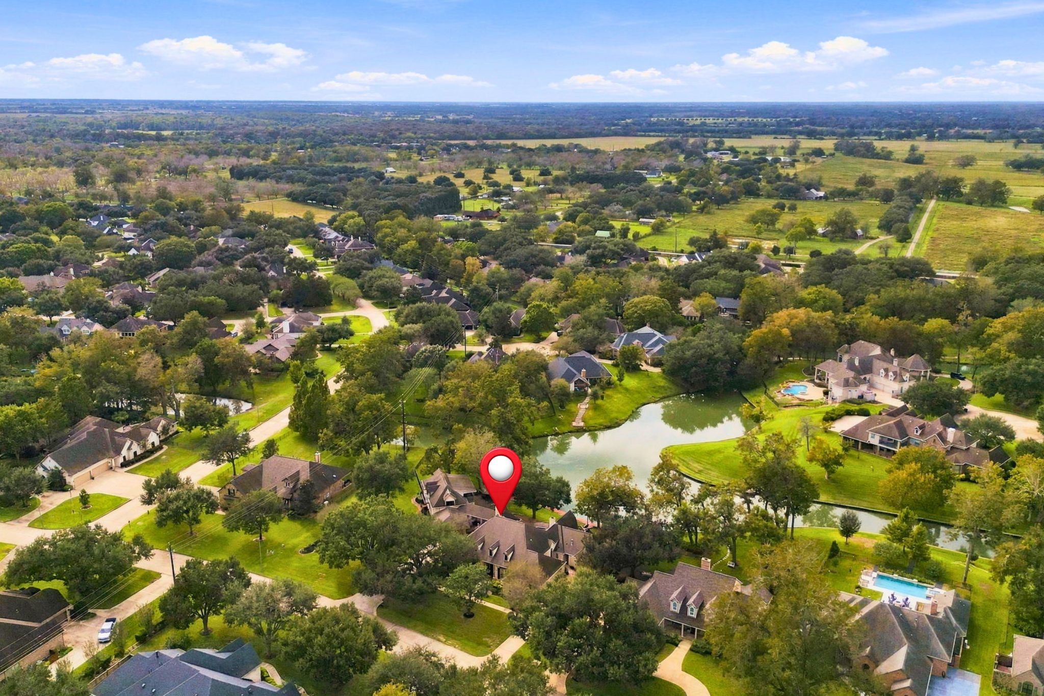 This aerial view looks west toward the front of the property, which is pinpointed for easy identification and to highlight its beautiful location within the community.