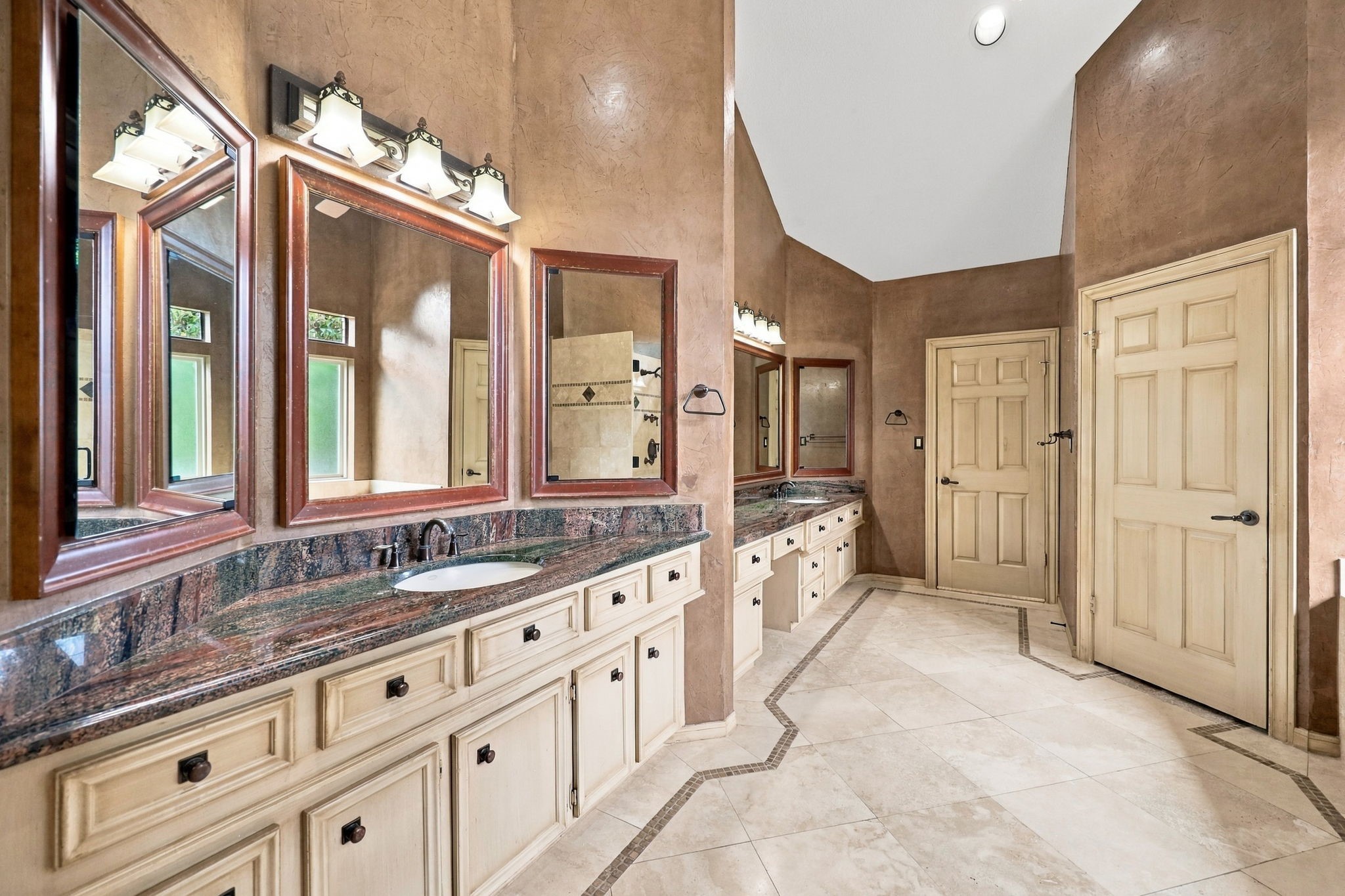 The spacious Primary Bath offers a touch of luxury with separate double vanity areas, gorgeous granite countertops, undermount sinks, and beautifully framed mirrors. Two large closets provide ample storage, while elegant tile finishes add to the appeal. This well-appointed space offers a wonderful blend of comfort, style, and functionality.