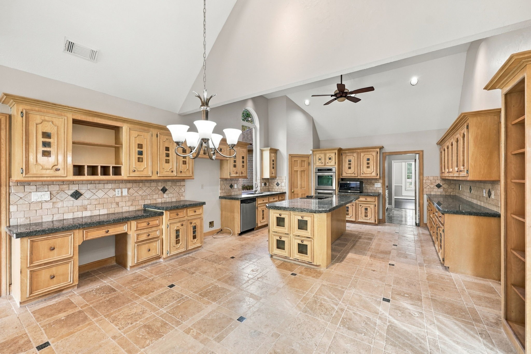 Looking in the opposite direction, you'll discover a convenient built-in desk area, offering an additional workspace perfect for managing household tasks, studying, or working from home. The Kitchen is beautifully appointed with tile flooring featuring a decorative pattern of varying tile sizes and accent pieces, gorgeous granite countertops, and a coordinating backsplash that completes the look.