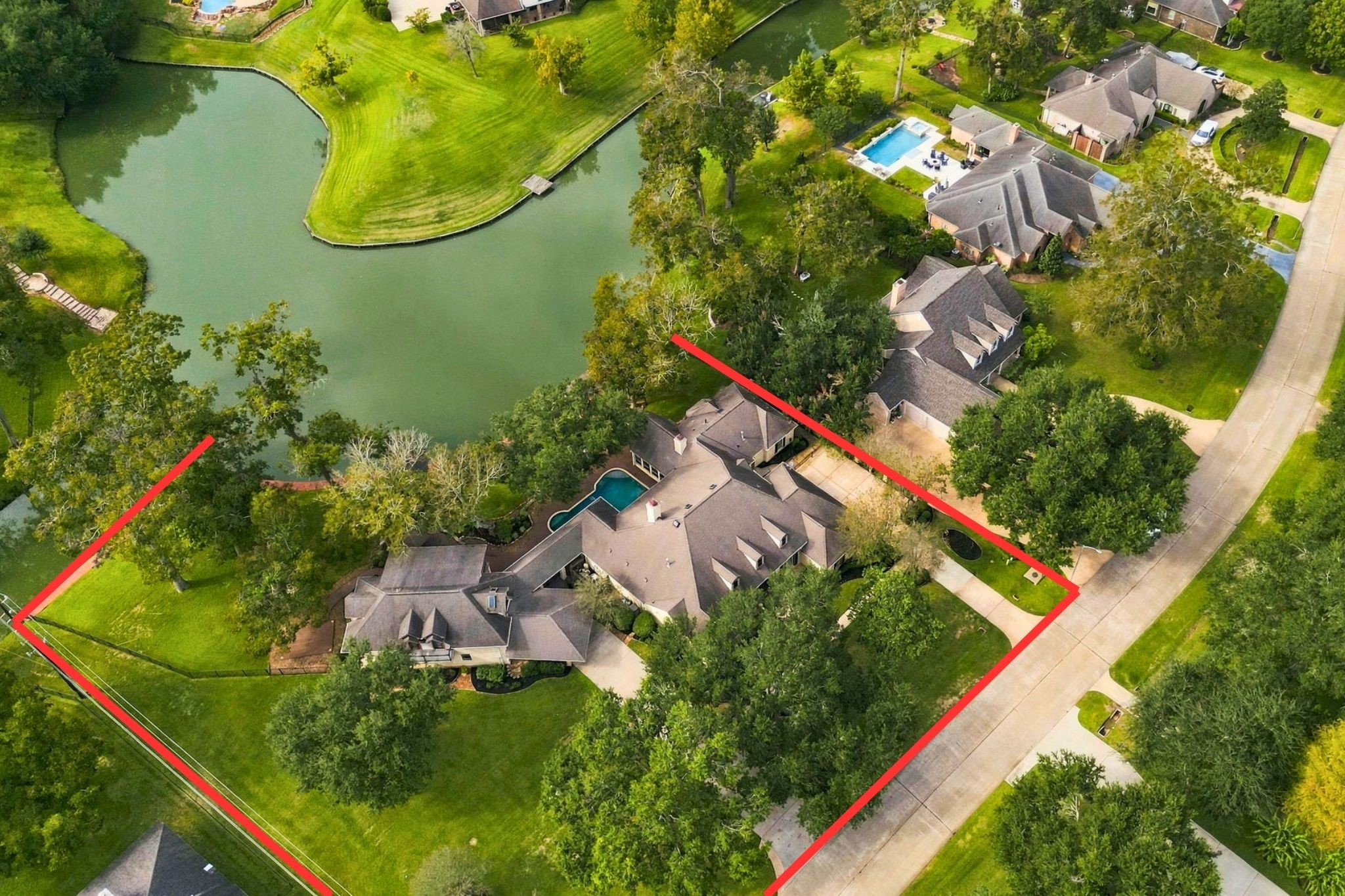 This aerial view captures the magnificent scale of the property and its beautiful waterfront setting, showcasing the expansive grounds, mature trees, and surrounding landscape. Property lines outlined in red are approximate and provided for illustrative purposes only.