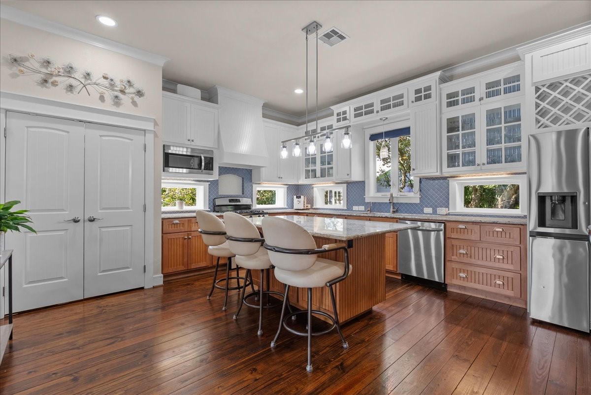 Spacious island kitchen with abundant cabinetry, counter seating and stainless appliances, boasting with natural light.