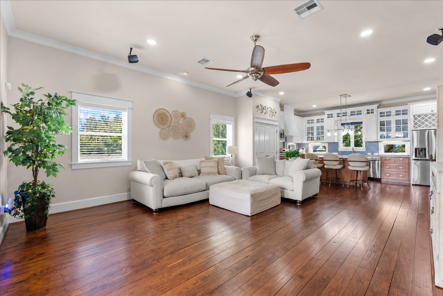 An elegant, light filled living space featuring hardwood floors, high ceilings, and an open concept design that flows seamlessly into the kitchen.