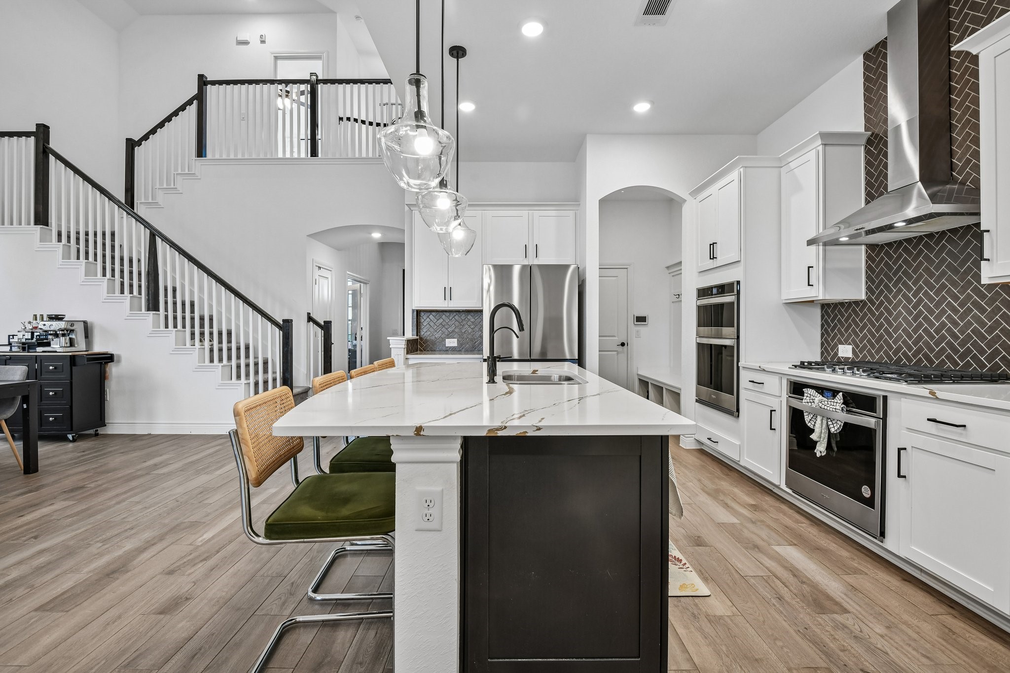 Open-concept main level connects the kitchen, dining space, family room, and staircase