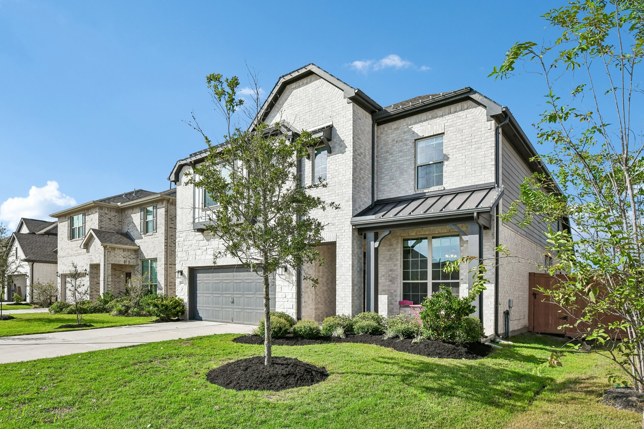 Full front exterior with herringbone brick detail, mixed masonry, and standing-seam metal roof accent