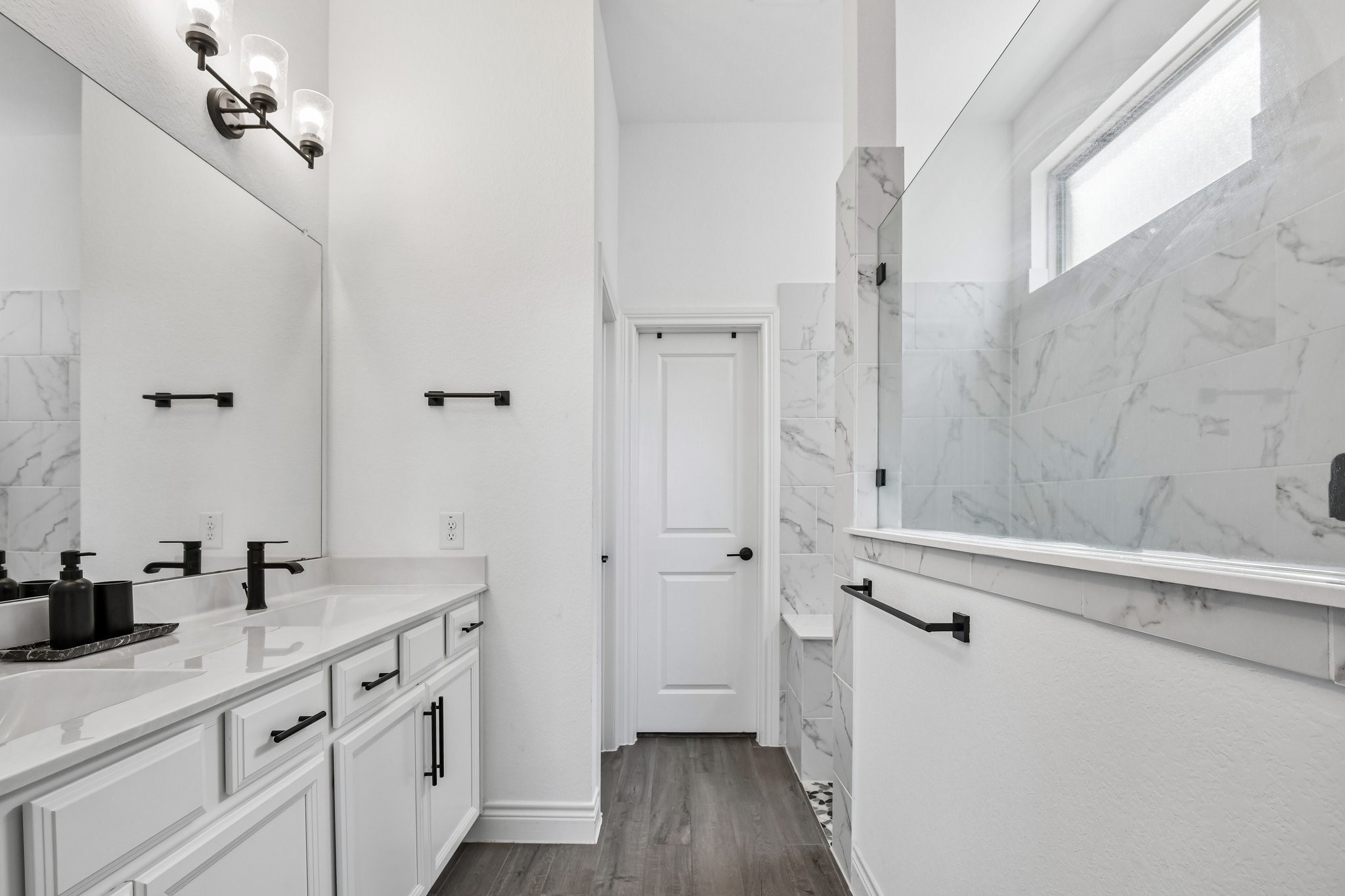 Marble-look primary bath with dual sinks, oversized glass walk-in shower, and walk-in closet