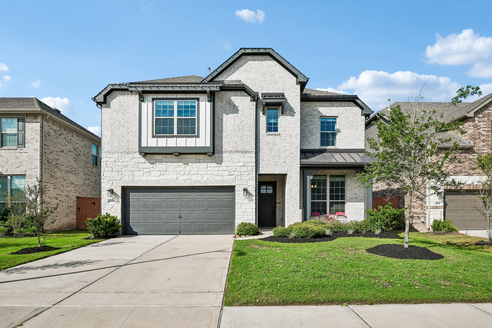 Wide front view showing the two-car garage, driveway, covered entry, and landscaped yard