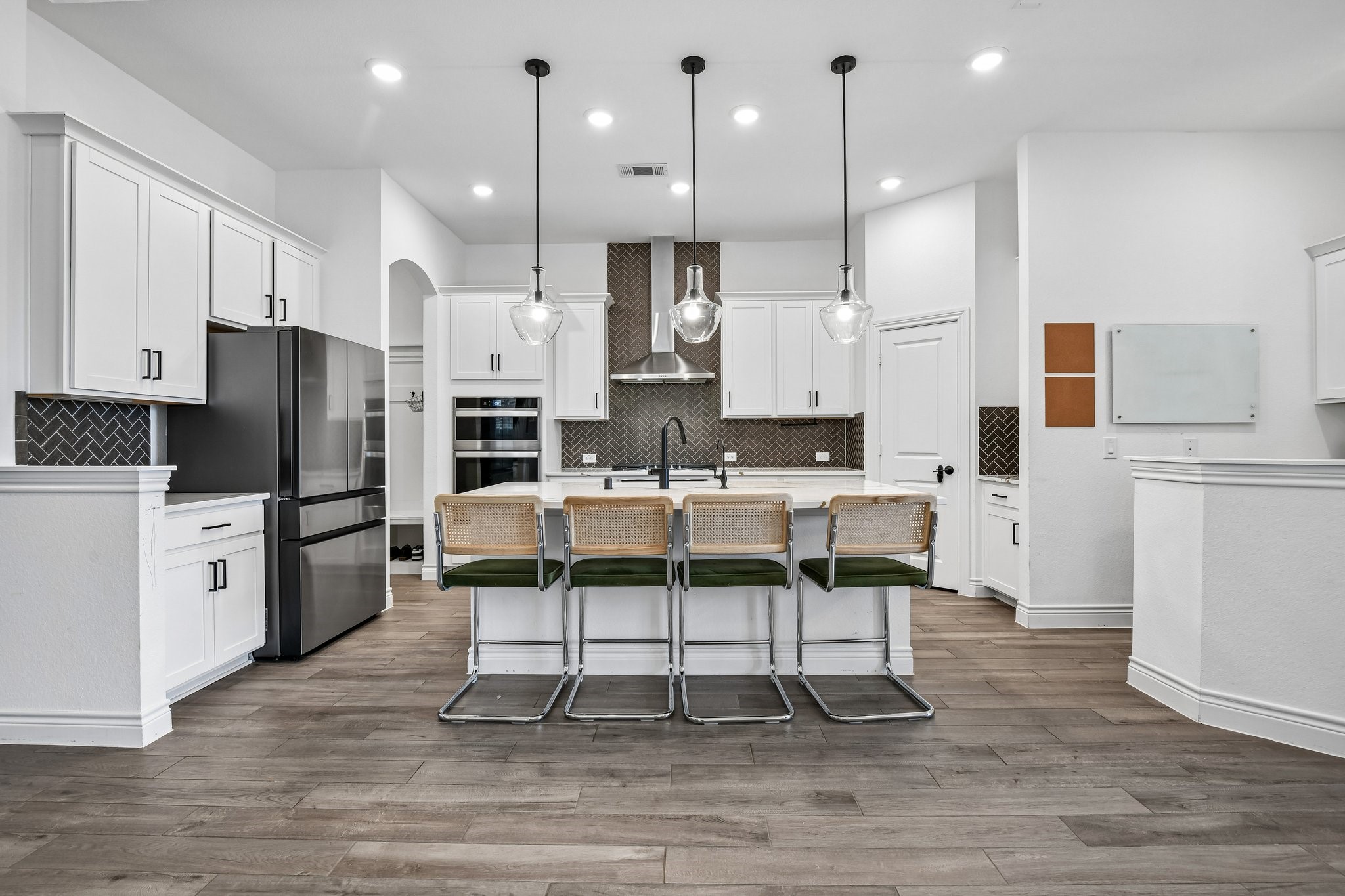 Oversized quartz island anchors the kitchen with generous seating, pendant lighting, and prep space