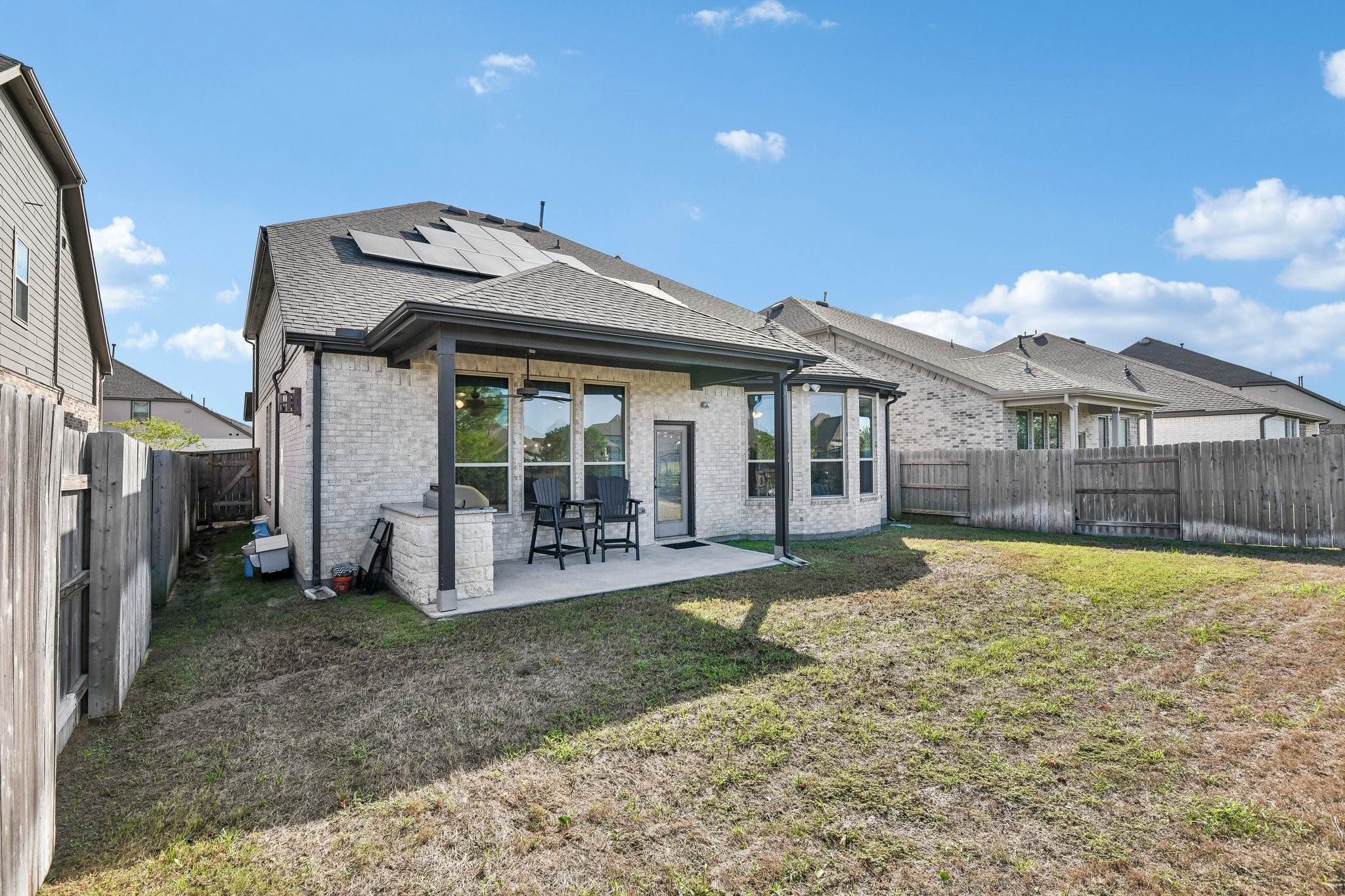 Rear three-quarter view showing the patio, fenced yard, and side access