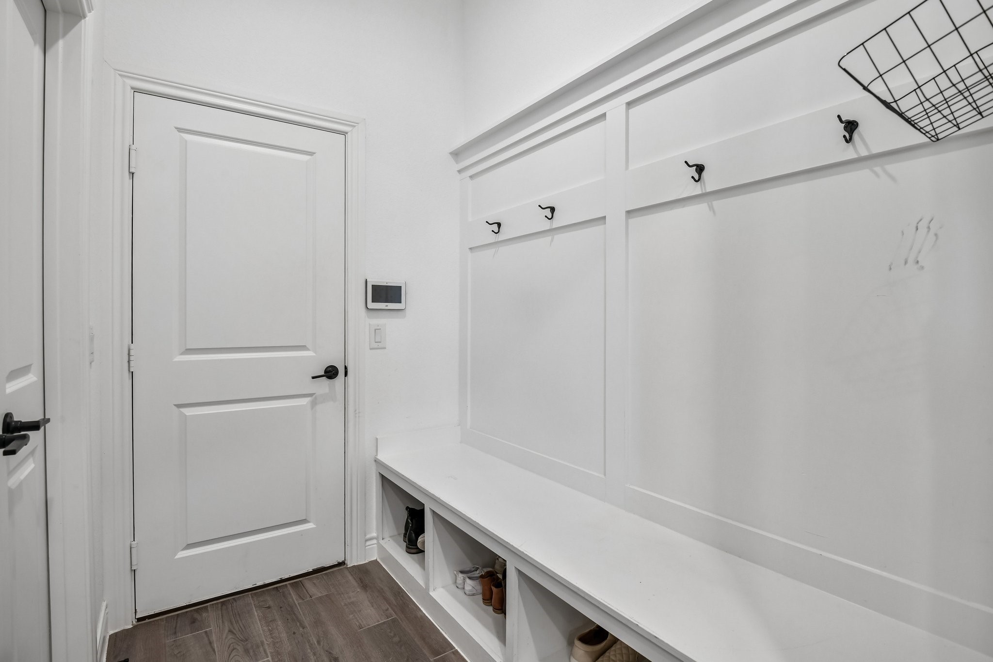 Mudroom drop zone with built-in bench, hooks, and convenient access to the laundry room and garage