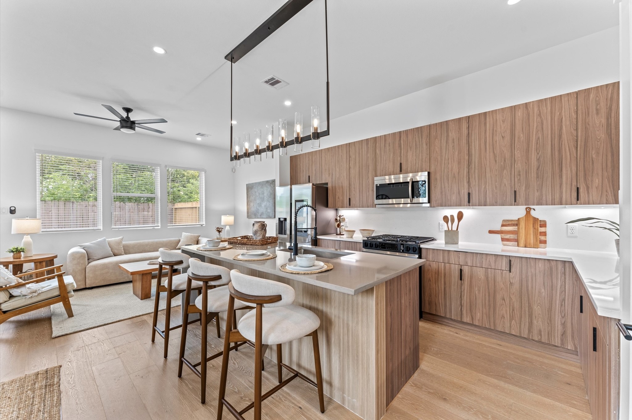 This stunning kitchen island is the centerpiece of a modern open-concept layout, featuring a waterfall quartz countertop that cascades elegantly down one side for high-end look. Positioned to offer clear sightlines to the living and dining areas, as well as through French doors to the balcony, the island enhances both functionality and flow. Contemporary finishessuch as sleek cabinetry, bold pendant lighting, and integrated appliancesadd sophistication, while bar seating invites casual dining.
