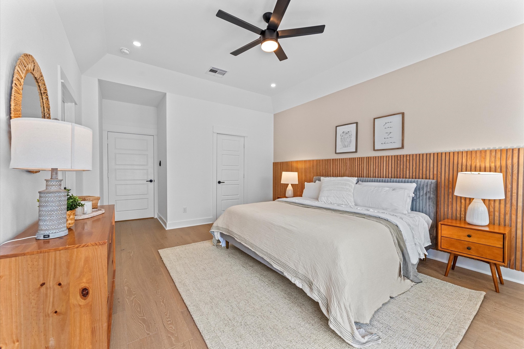 This elegant second-floor primary bedroom offers a luxurious retreat with soaring high ceilings that amplify the sense of space and grandeur. The room is anchored by engineered hardwood flooring, adding warmth and sophistication to the contemporary design. A massive walk-in closet provides boutique-style storage with custom shelving and ample room for wardrobe organization.