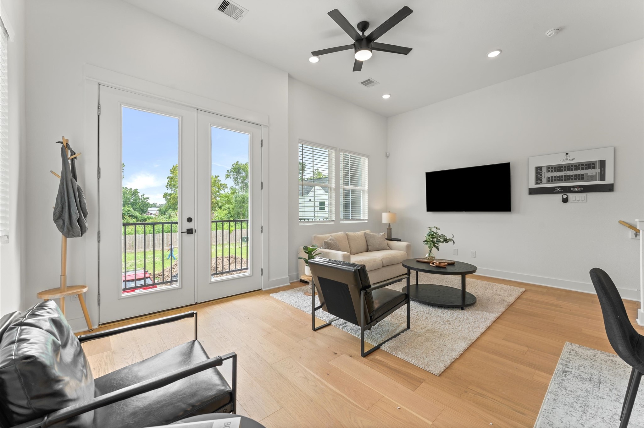 Airy and inviting open-concept living space located on the second floor, thoughtfully designed to enhance both comfort and flow. The area features high ceilings, expansive windows, and cohesive flooring that unify the living, dining, and kitchen zones. Elegant French doors serve as a striking focal point, leading out to a private balcony that extends the living space outdoorsperfect for morning coffee or evening unwinding.