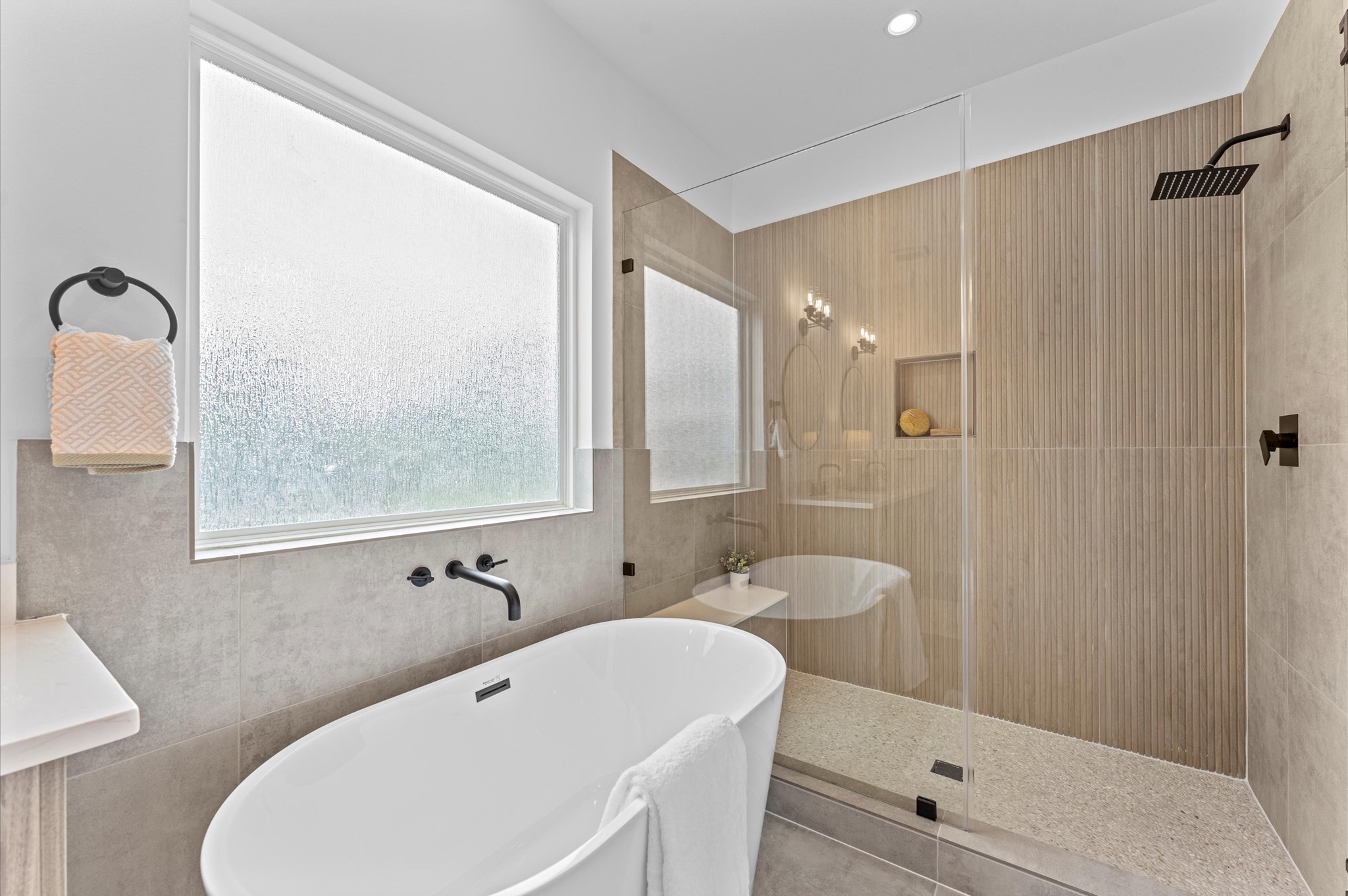 This luxurious primary bathroom blends modern elegance with spa-like comfort, featuring a spacious layout and contemporary selections throughout. A sleek double vanity with minimalist cabinetry and quartz countertops offers ample storage and style, while the glass-enclosed shower includes a built-in bench for added relaxation and convenience. The centerpiece is a sculptural freestanding soaking tub, perfectly positioned to invite unwinding after a long day.
