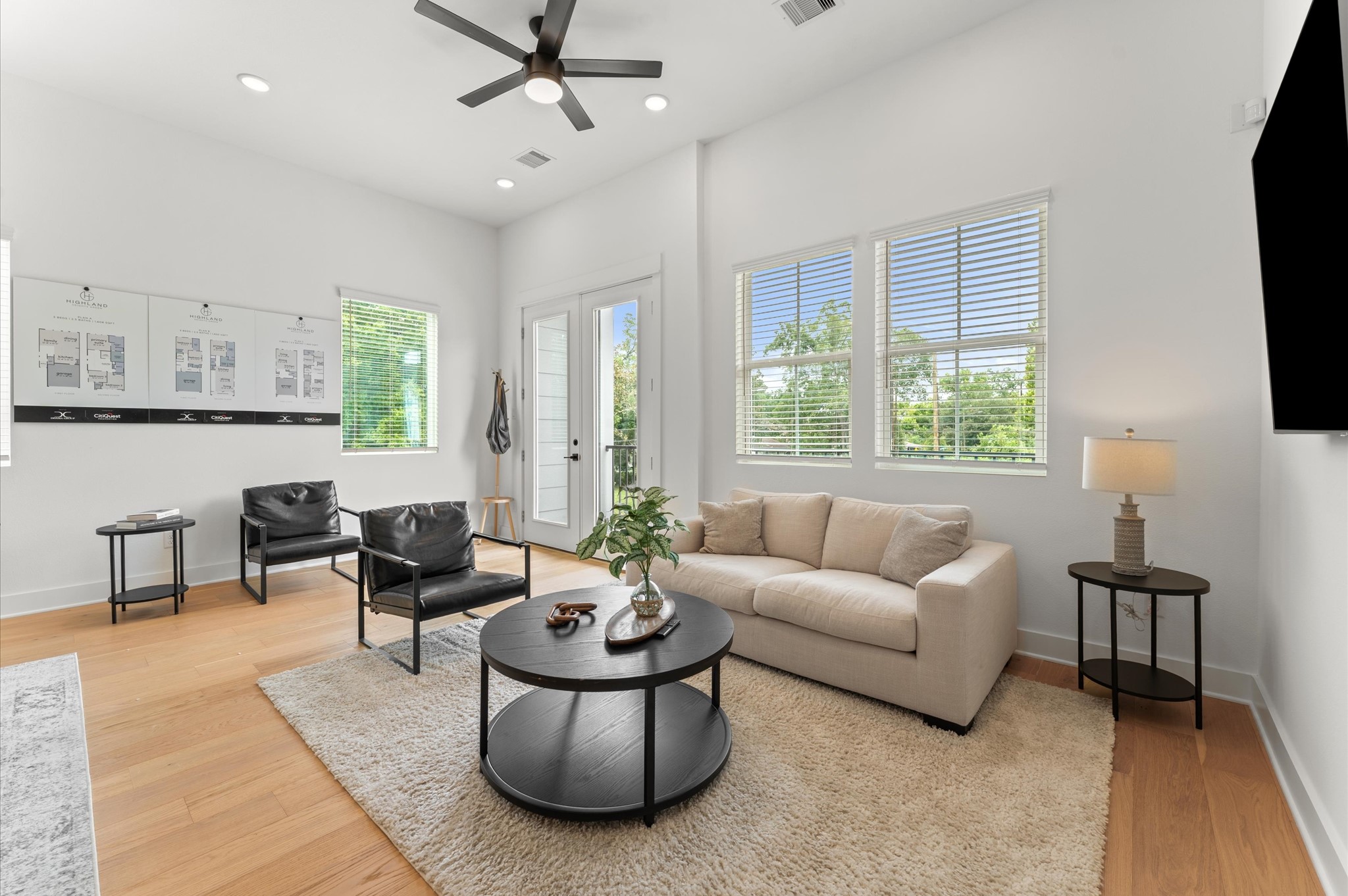 Airy and inviting open-concept living space located on the second floor, thoughtfully designed to enhance both comfort and flow. The area features high ceilings, expansive windows, and cohesive flooring that unify the living, dining, and kitchen zones. Elegant French doors serve as a striking focal point, leading out to a private balcony that extends the living space outdoorsperfect for morning coffee or evening unwinding.