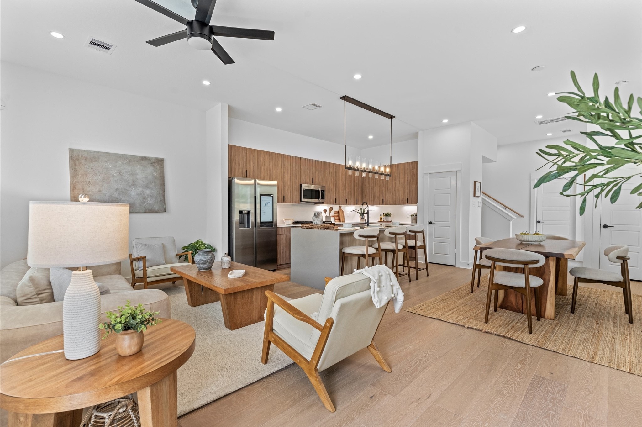 Expansive and light-filled open-concept layout seamlessly combining the living room, dining area, and kitchen on the second floor. The space boasts high ceilings, wide windows for abundant natural light, and elegant flooring that ties the zones together beautifully. The kitchen features modern cabinetry, sleek countertops, and a center island with bar seatingperfect for entertaining or casual meals. Adjacent dining area easily accommodates a full-size table, while the living space is inviting!