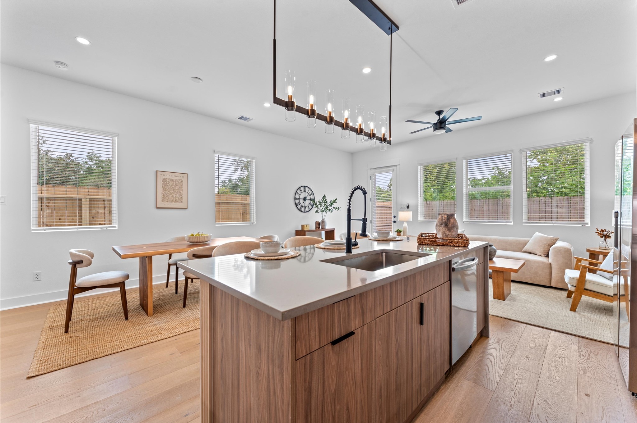 Airy and inviting open-concept living space located on the second floor, thoughtfully designed to enhance both comfort and flow. The area features high ceilings, expansive windows, and cohesive flooring that unify the living, dining, and kitchen zones. Elegant French doors serve as a striking focal point, leading out to a private balcony that extends the living space outdoorsperfect for morning coffee or evening unwinding.