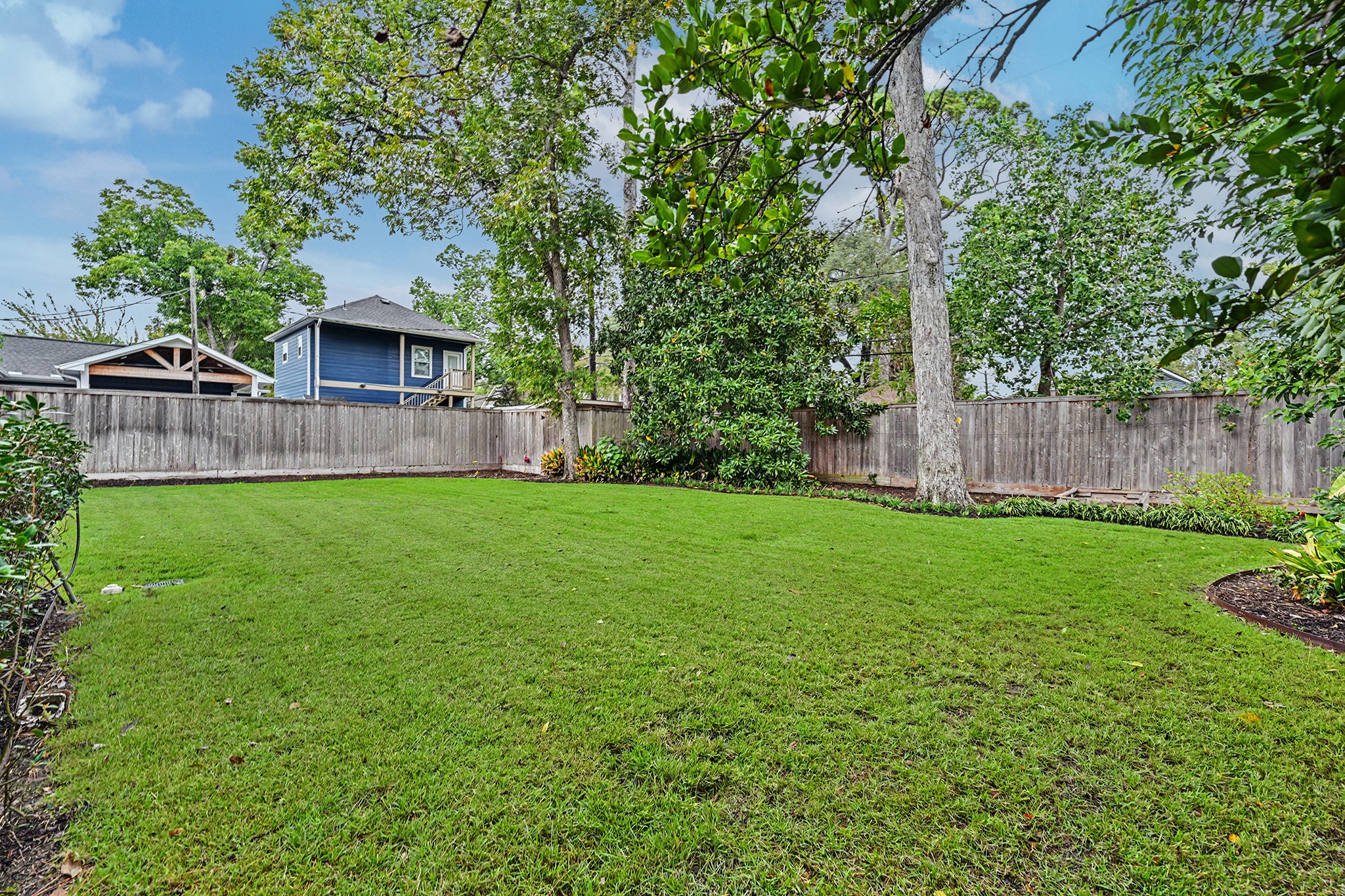 Another view of the expansive backyard highlights the generous lawn, mature trees and attractive landscaping.
